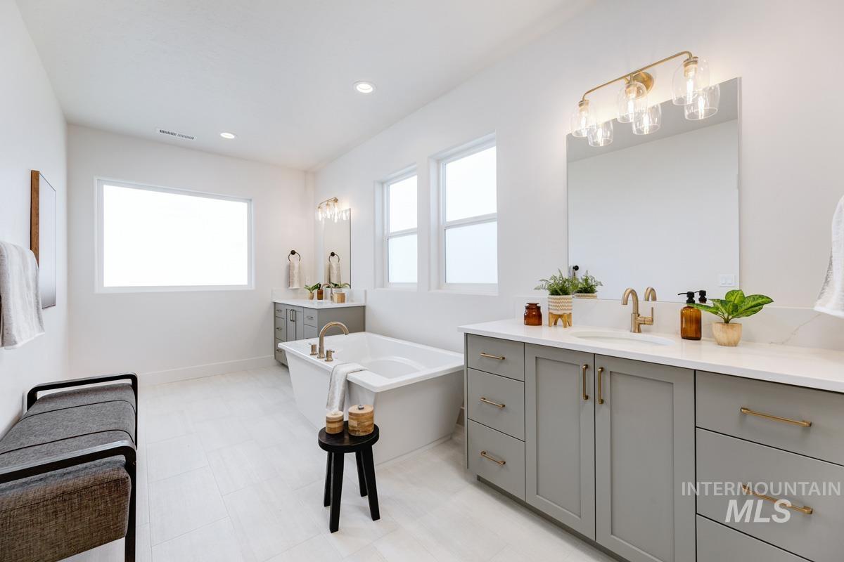 Bathroom with two vanities, a freestanding tub, and recessed lighting