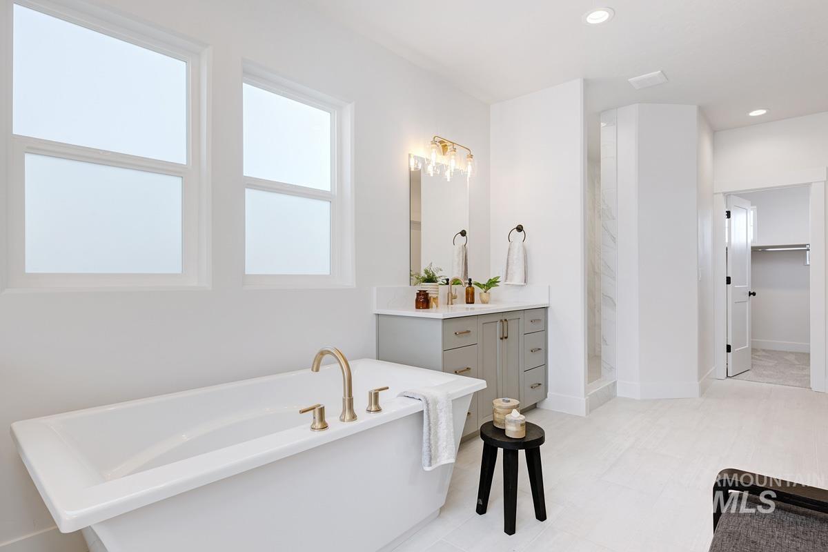 Full bathroom with vanity, a freestanding tub, recessed lighting, a shower stall, and a spacious closet