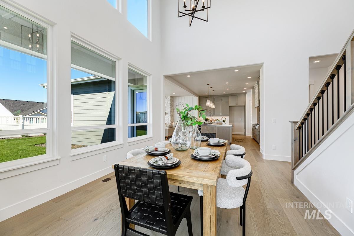 Dining area featuring a chandelier, light wood-style floors, a towering ceiling, stairs, and recessed lighting