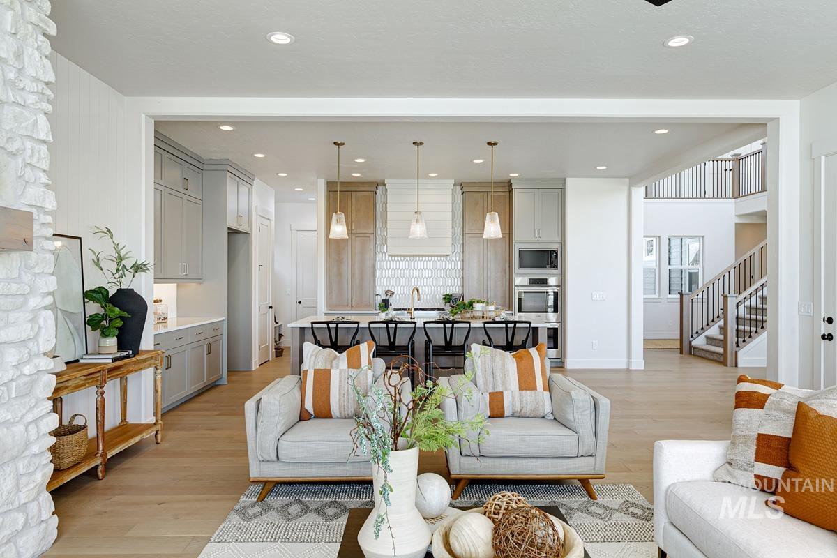 Living room with light wood-style floors, stairs, and recessed lighting