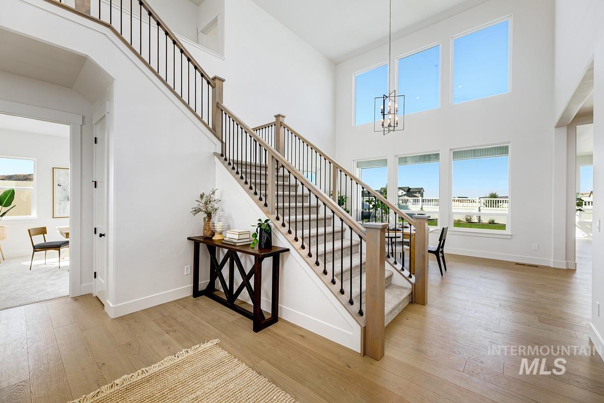 Stairs featuring wood-type flooring, plenty of natural light, a chandelier, and a towering ceiling