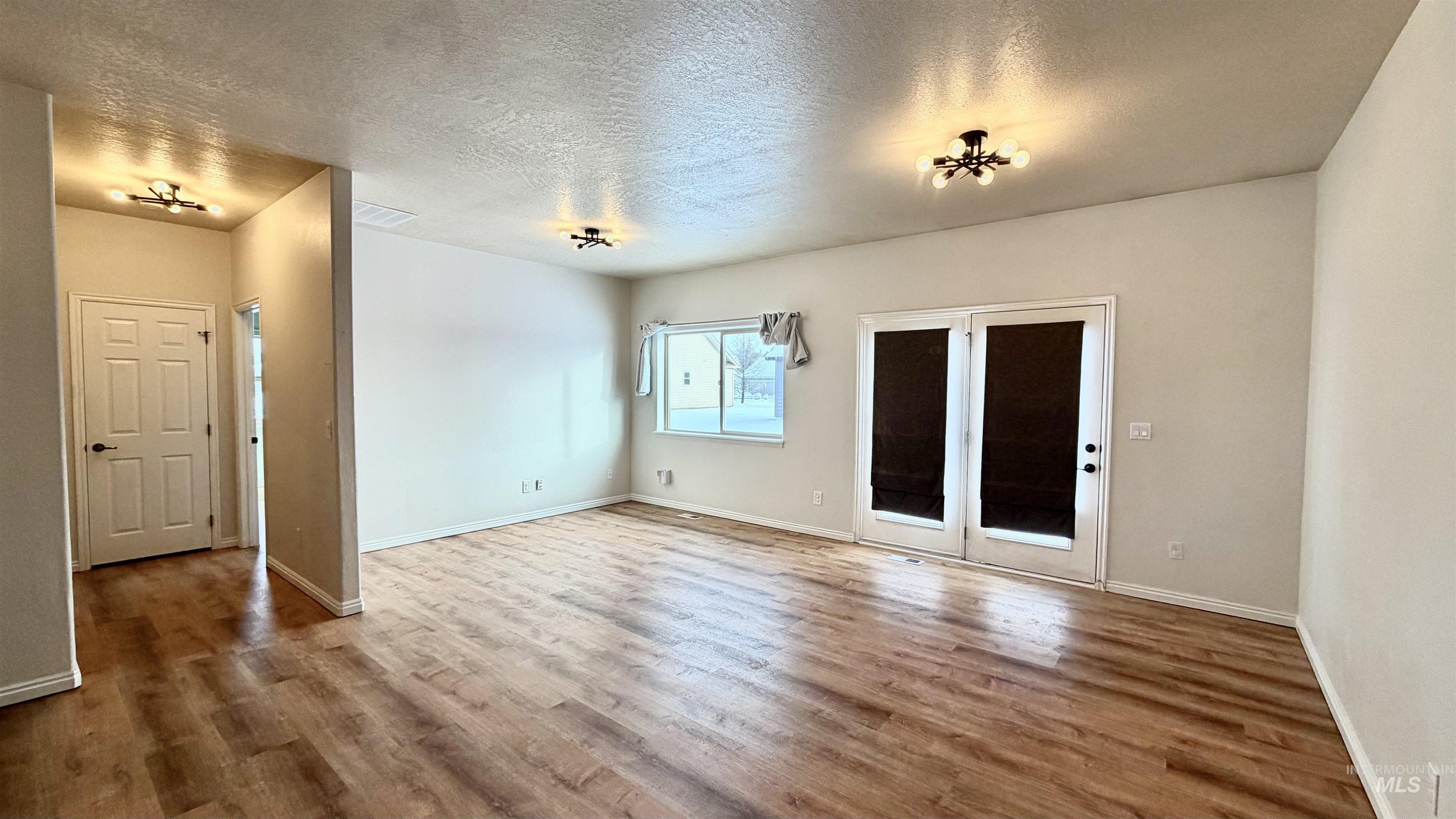 Empty room with a textured ceiling and wood finished floors
