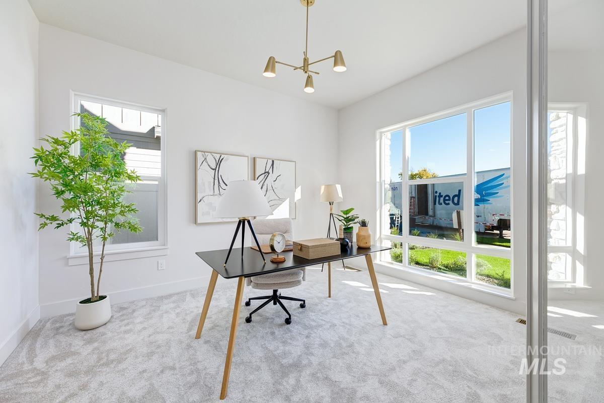 Home office featuring plenty of natural light, carpet, and a chandelier