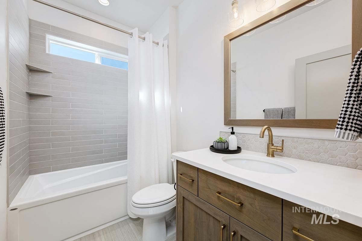 Bathroom with shower / bath combination with curtain, vanity, and decorative backsplash