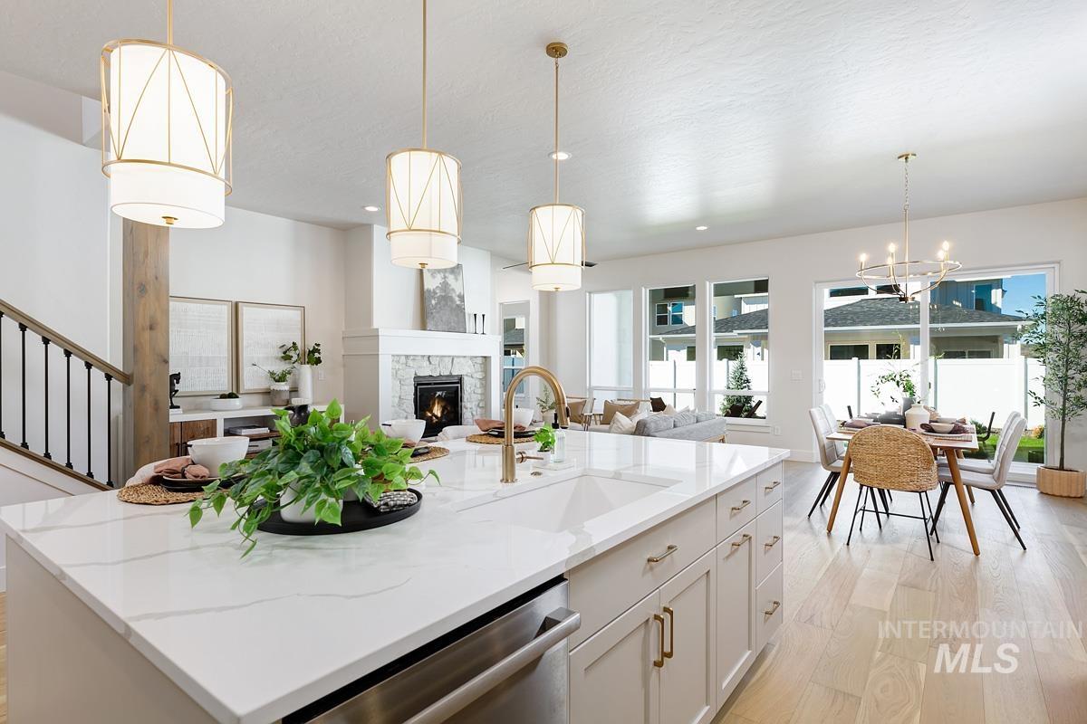 Kitchen with decorative light fixtures, white cabinets, dishwasher, an island with sink, and open floor plan