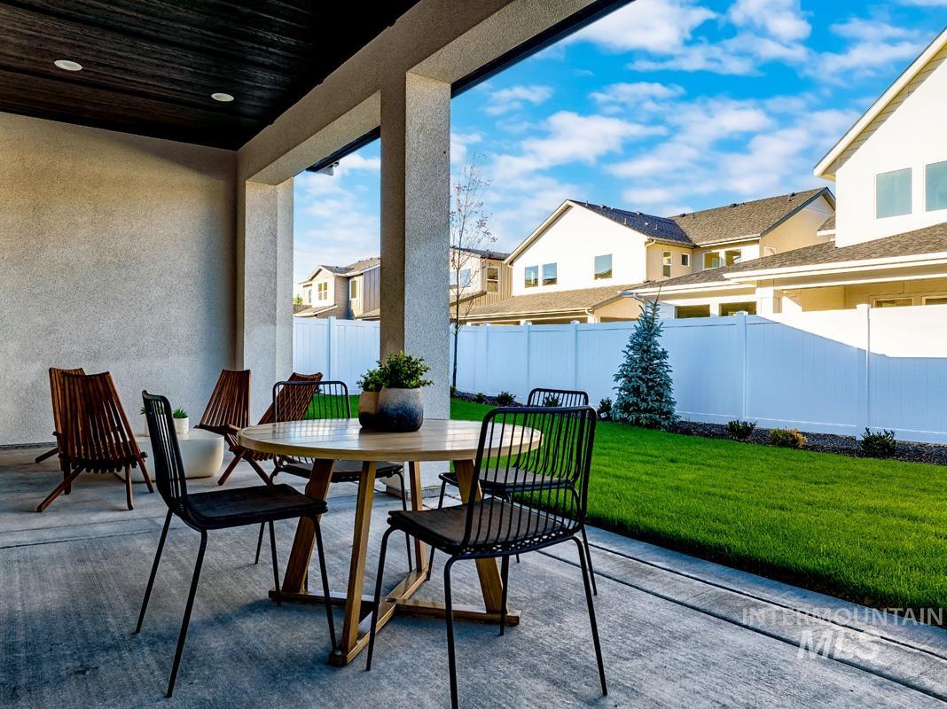 Fenced backyard featuring a patio, outdoor dining space, and a residential view