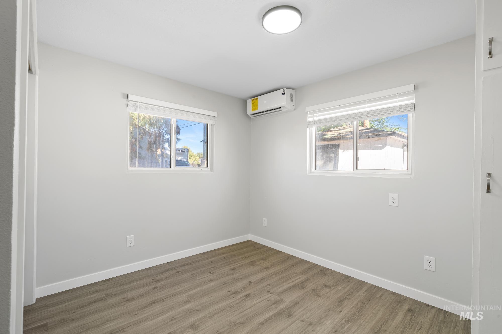 Unfurnished bedroom featuring wood finished floors, a closet, and a wall mounted air conditioner