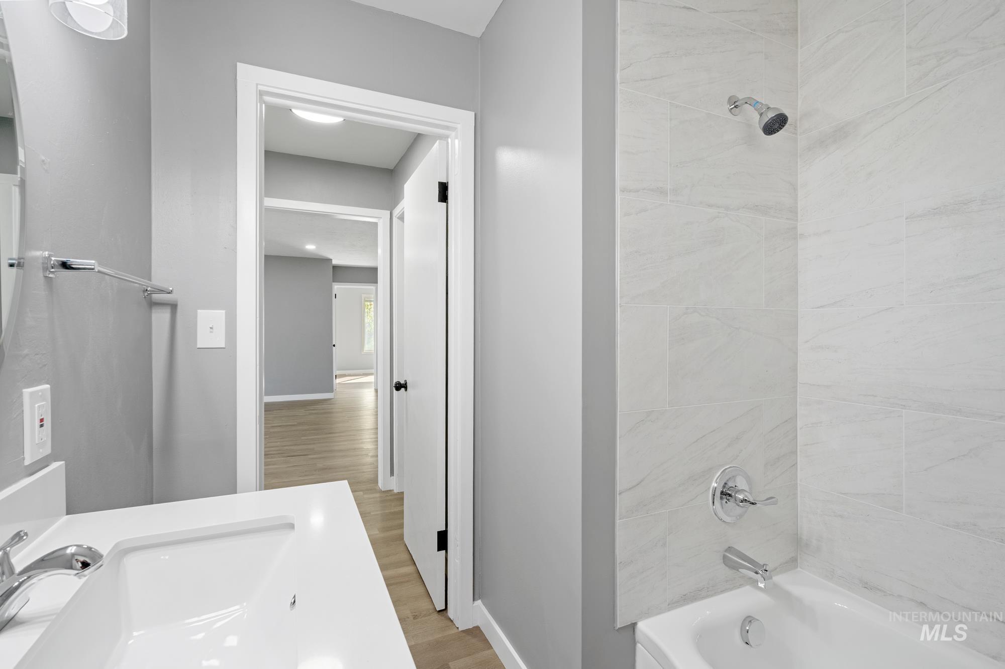 Bathroom with tub / shower combination, light wood-style floors, and vanity