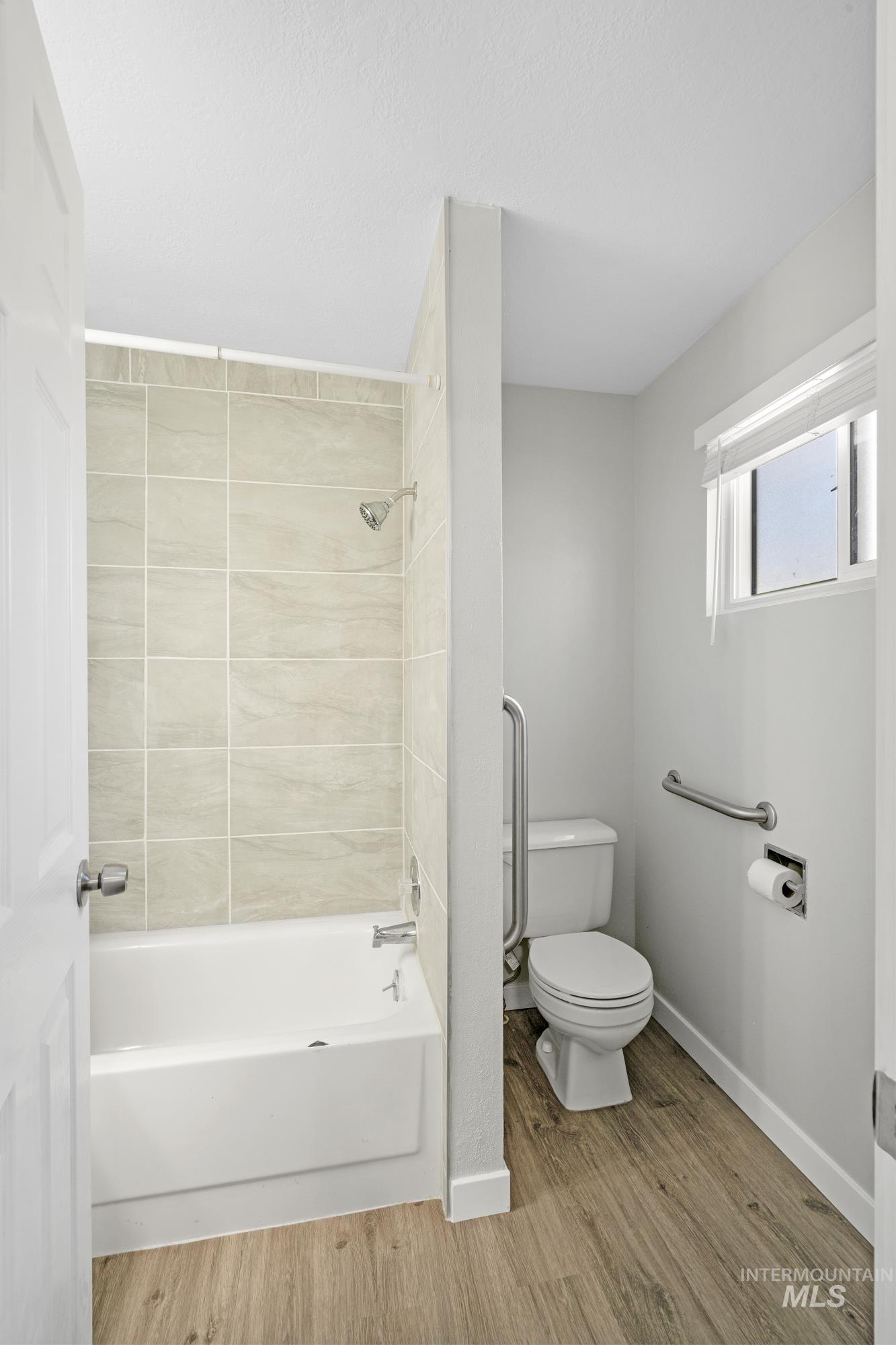 Full bath featuring tub / shower combination and light wood-style floors