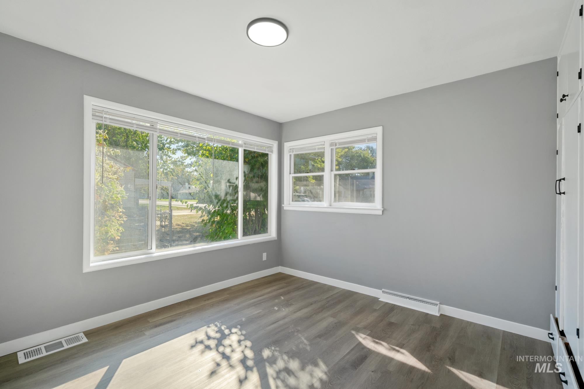 Unfurnished room featuring healthy amount of natural light and wood finished floors