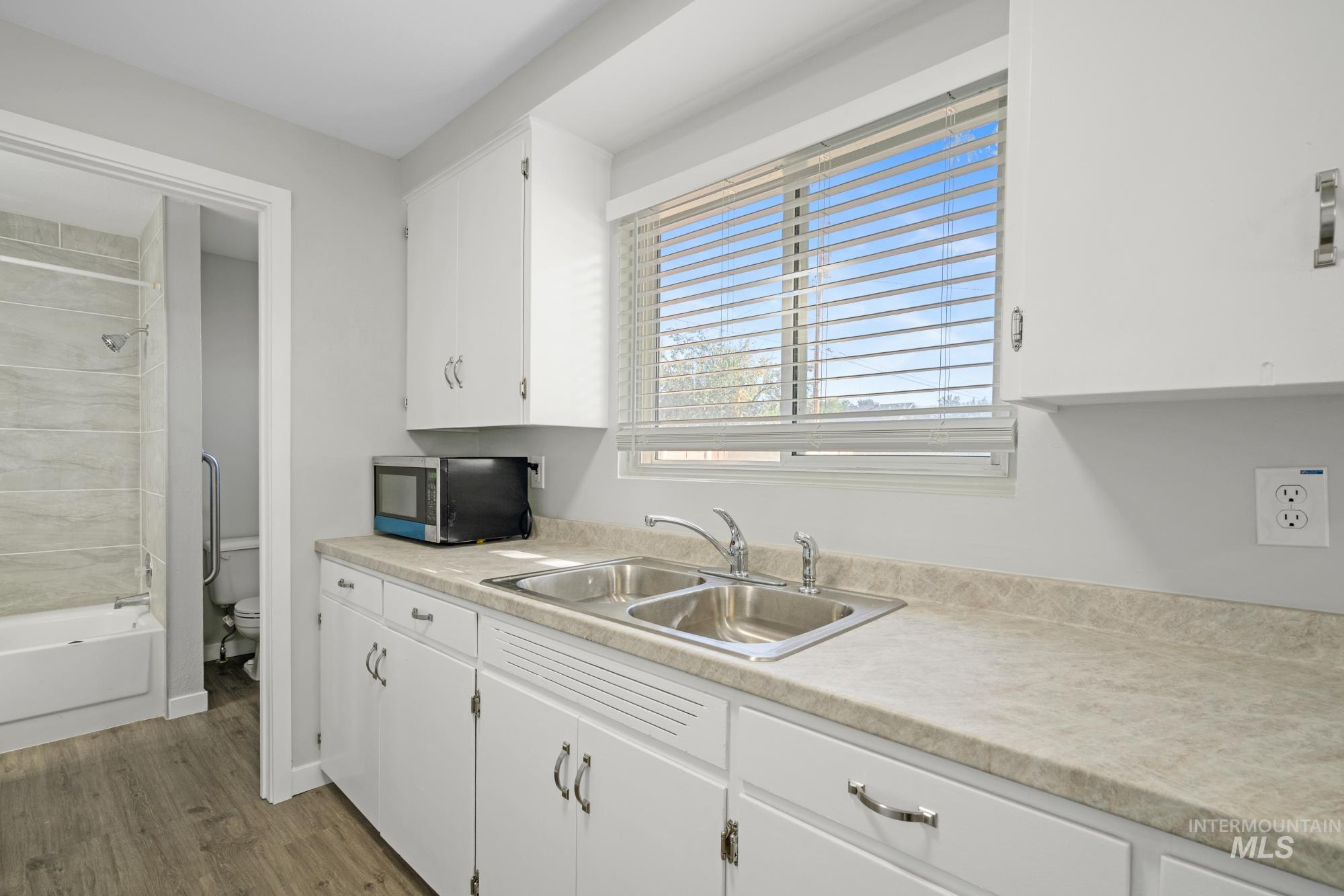 Kitchen featuring white cabinetry, light countertops, and wood finished floors