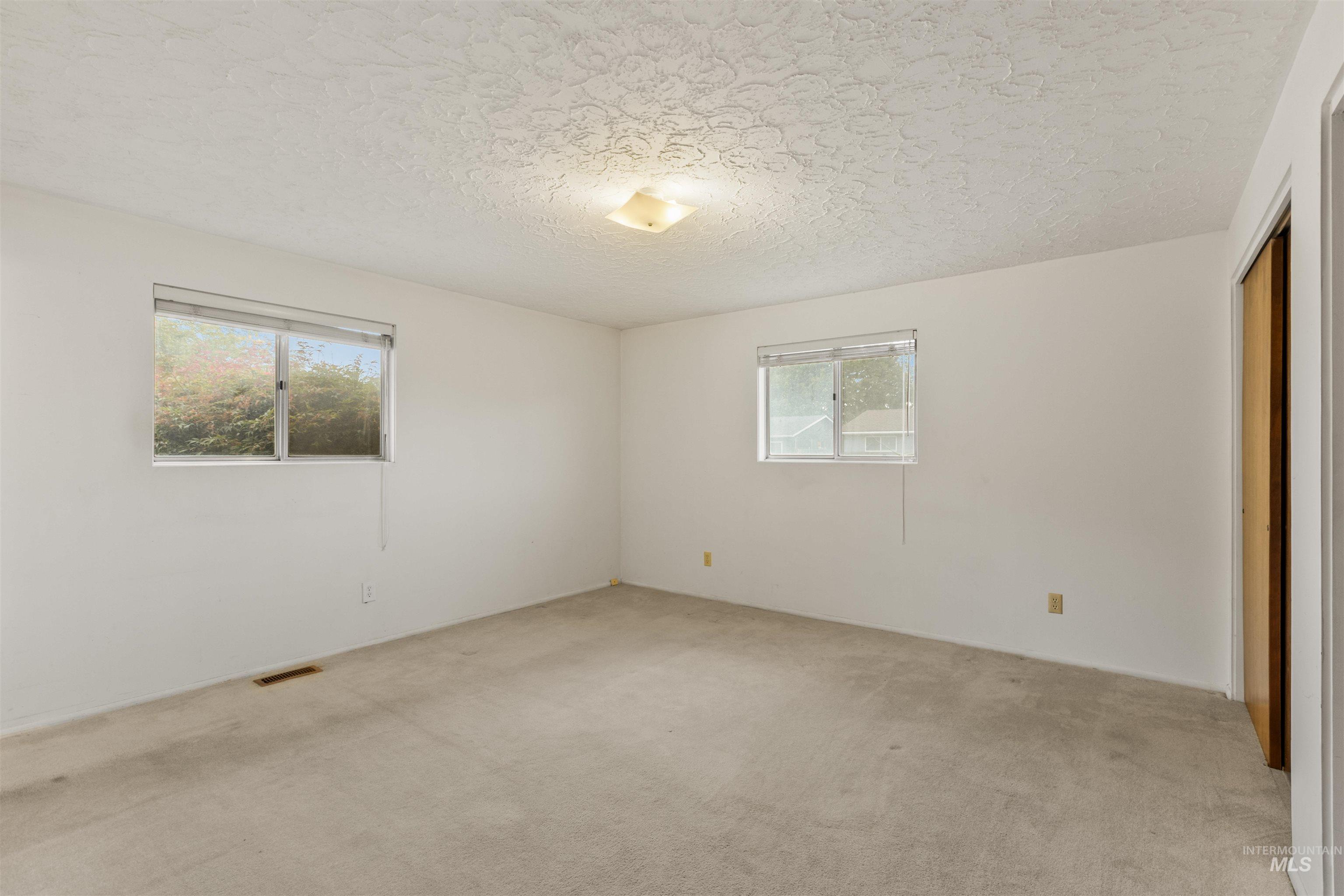 Unfurnished bedroom with a closet, light colored carpet, and a textured ceiling