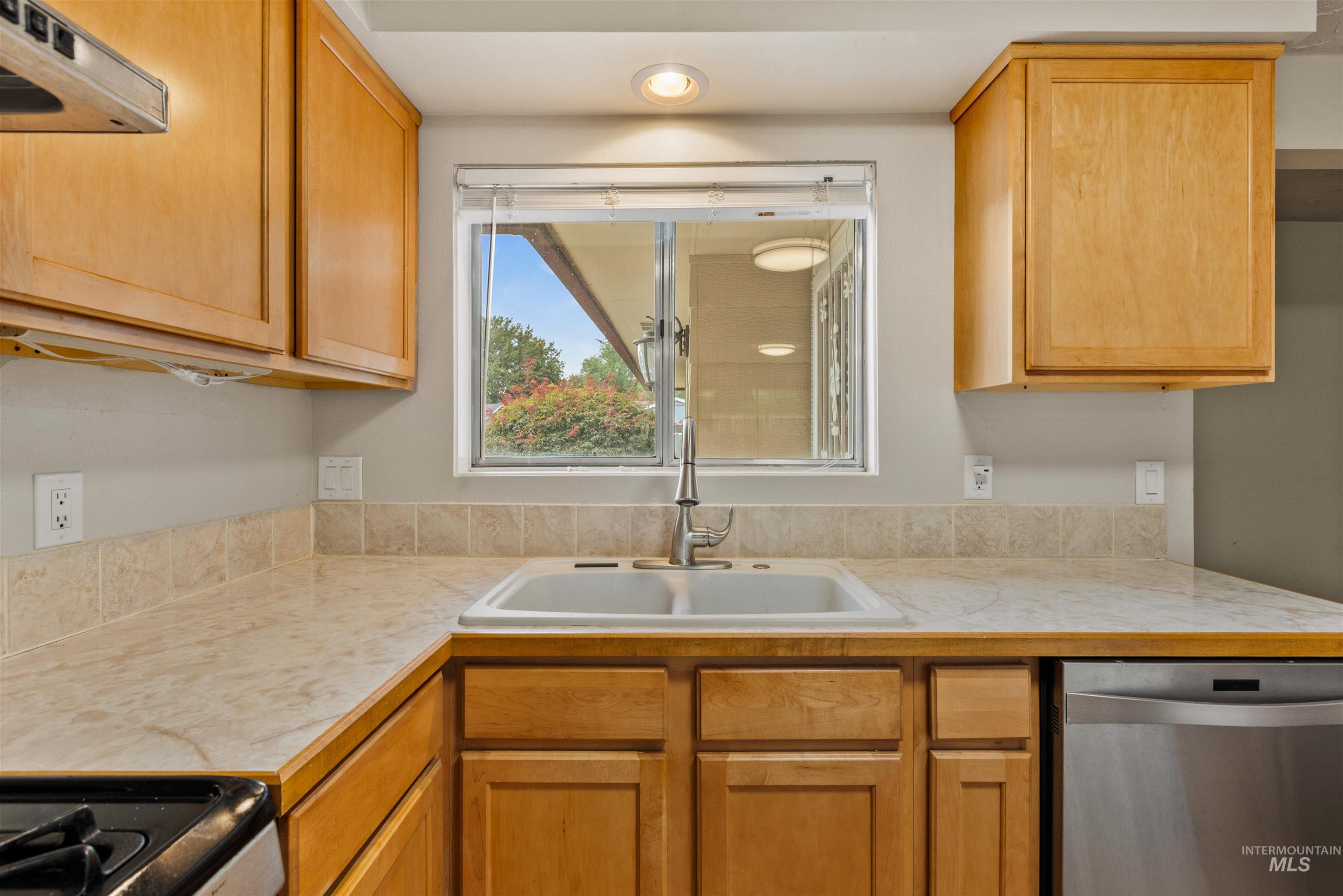 Kitchen with light countertops, stainless steel appliances, and under cabinet range hood
