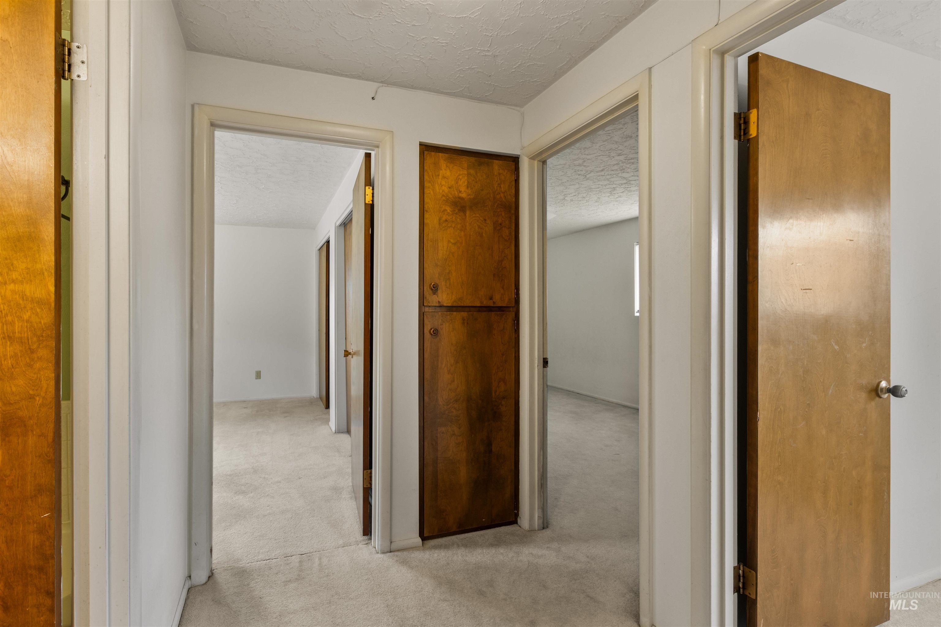 Hallway with a textured ceiling and light carpet
