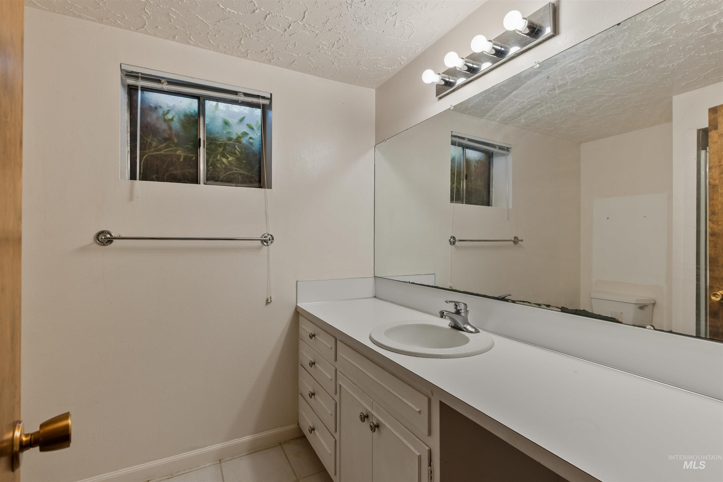 Bathroom featuring a textured ceiling, vanity, and light tile patterned flooring