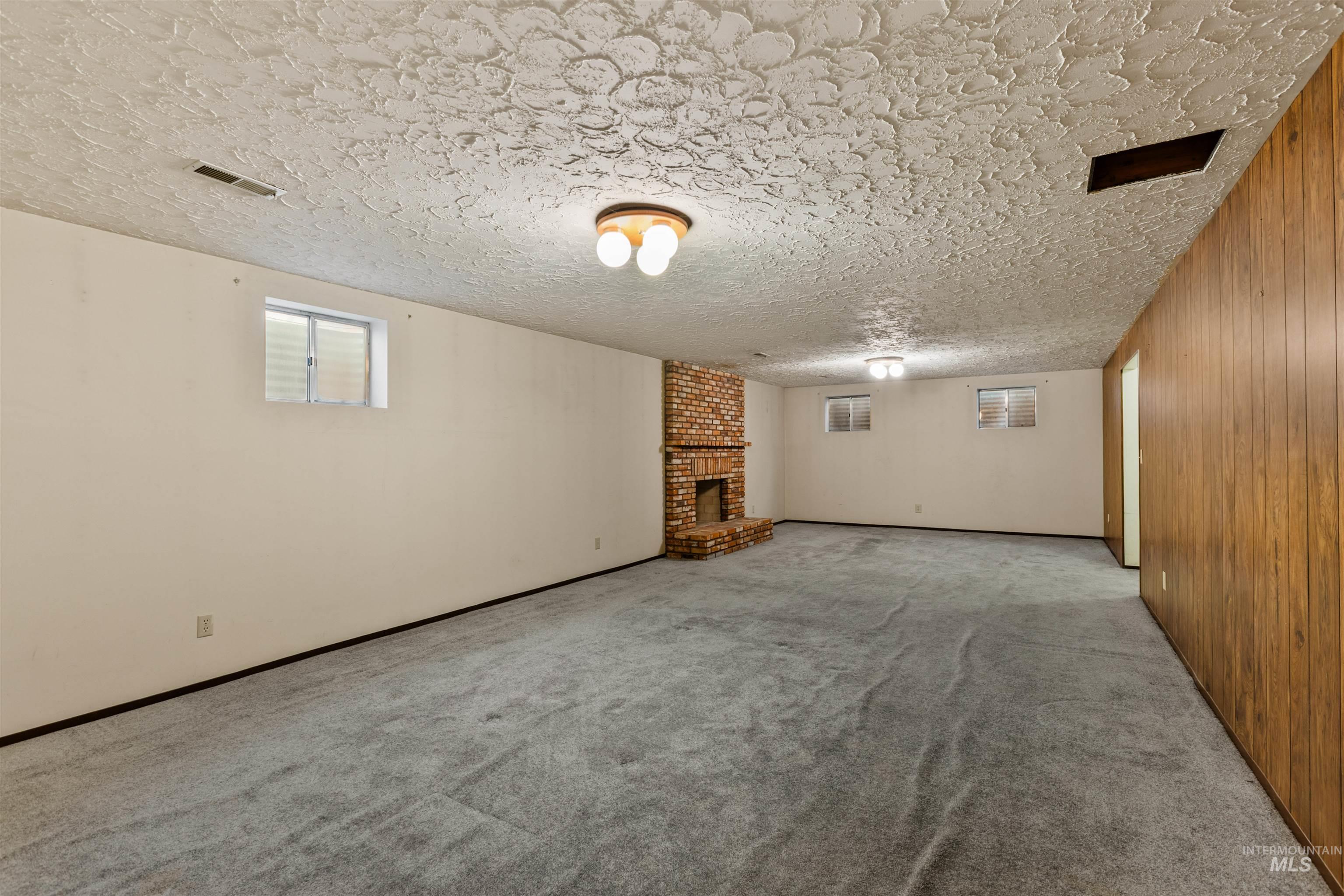 Below grade area featuring carpet, a fireplace, a textured ceiling, and wood walls