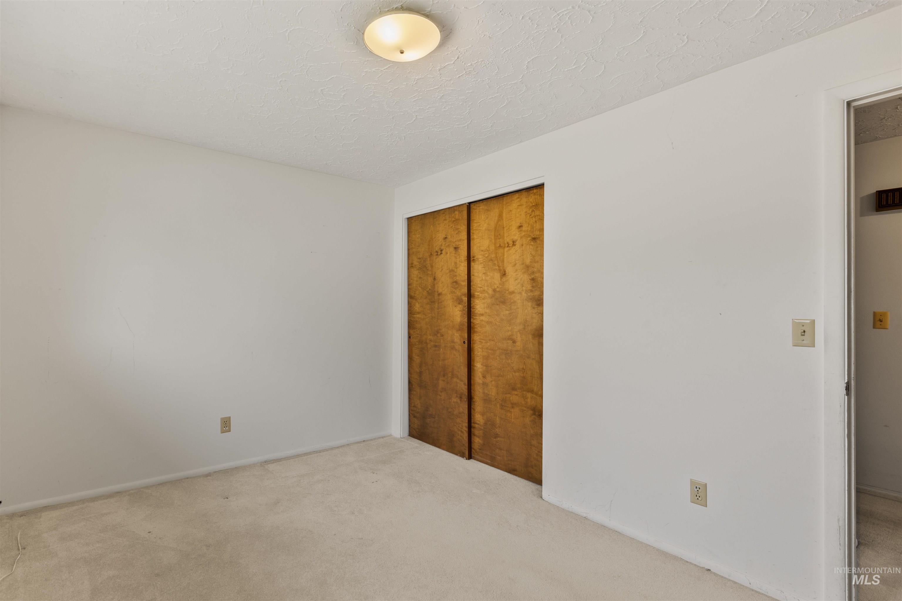 Unfurnished bedroom with a textured ceiling, carpet floors, and a closet
