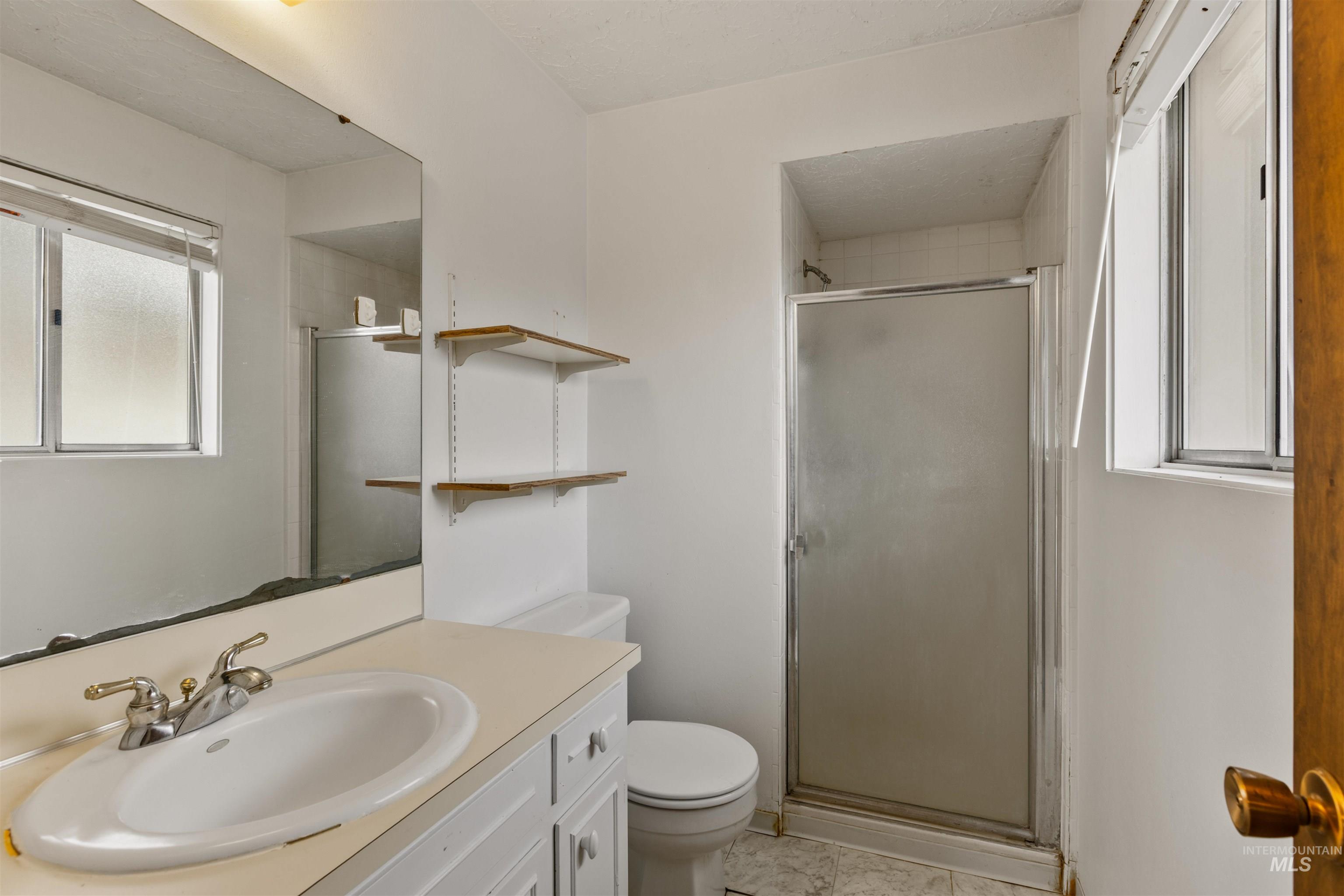 Full bath featuring vanity, a shower stall, and light tile patterned floors