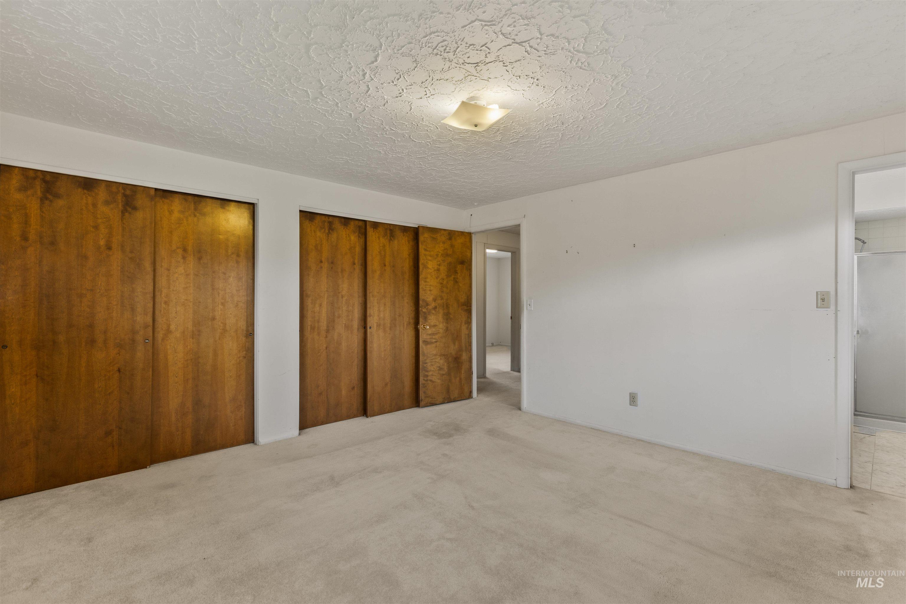 Unfurnished bedroom featuring two closets, carpet, and a textured ceiling