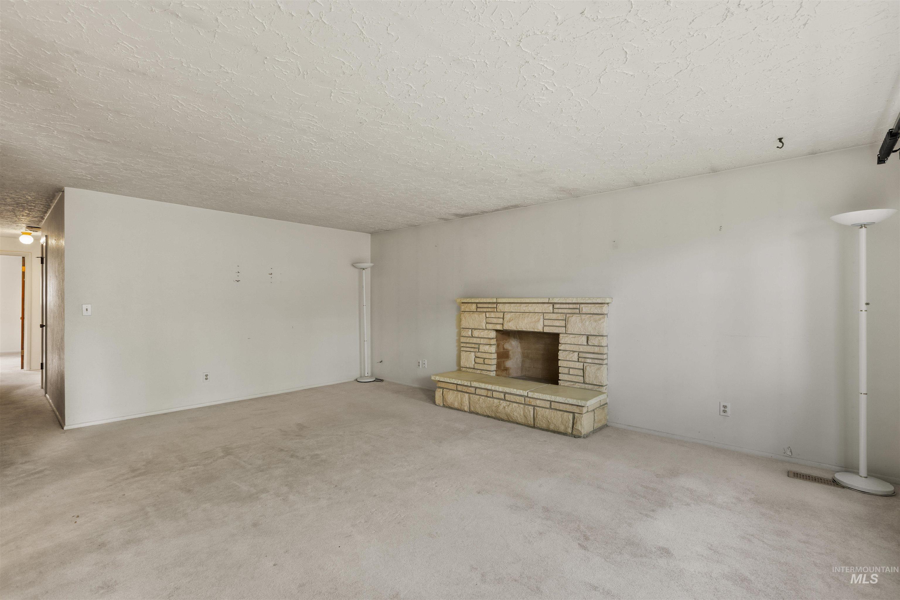 Unfurnished living room featuring a fireplace, carpet, and a textured ceiling