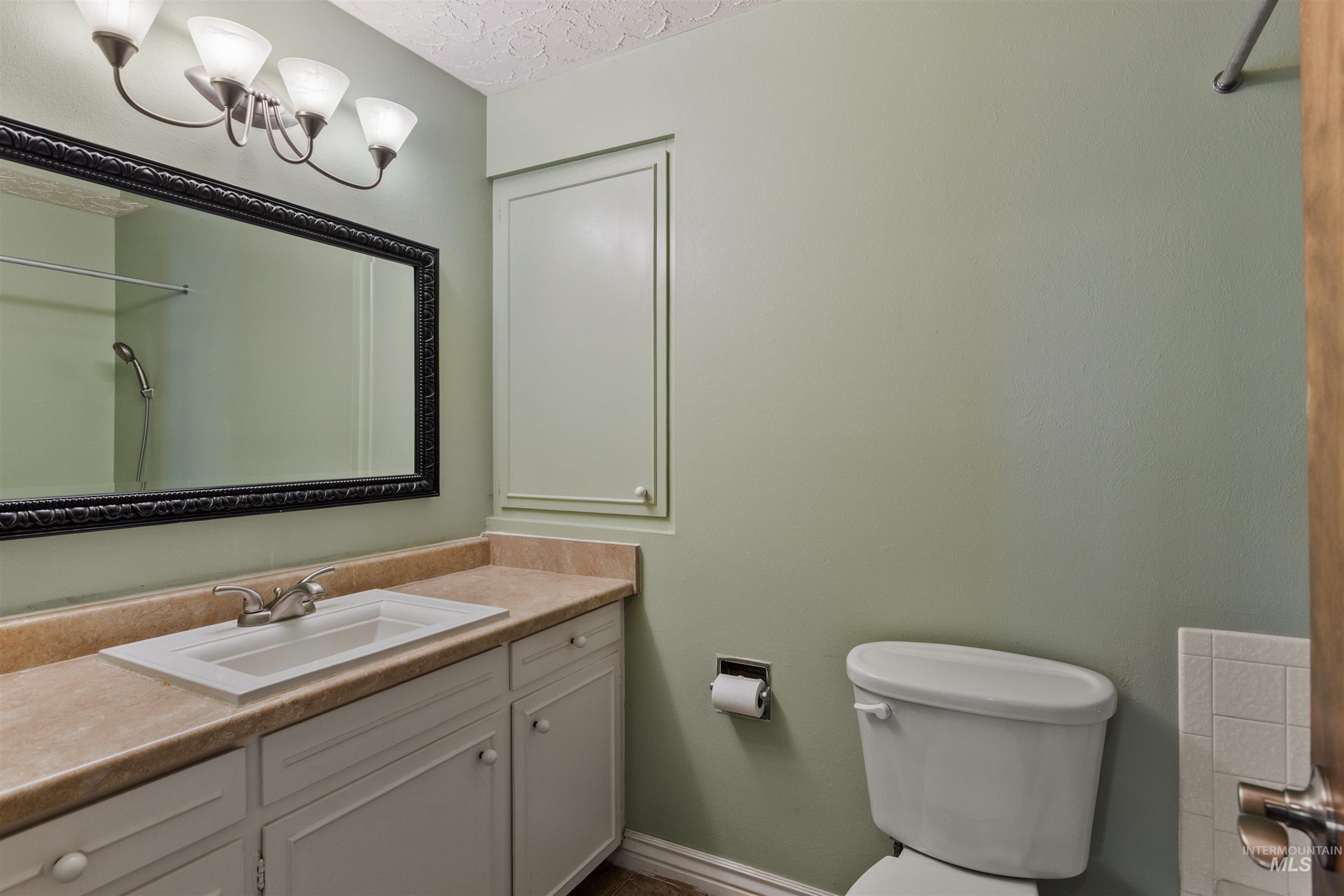 Full bathroom featuring vanity, a textured ceiling, and a chandelier