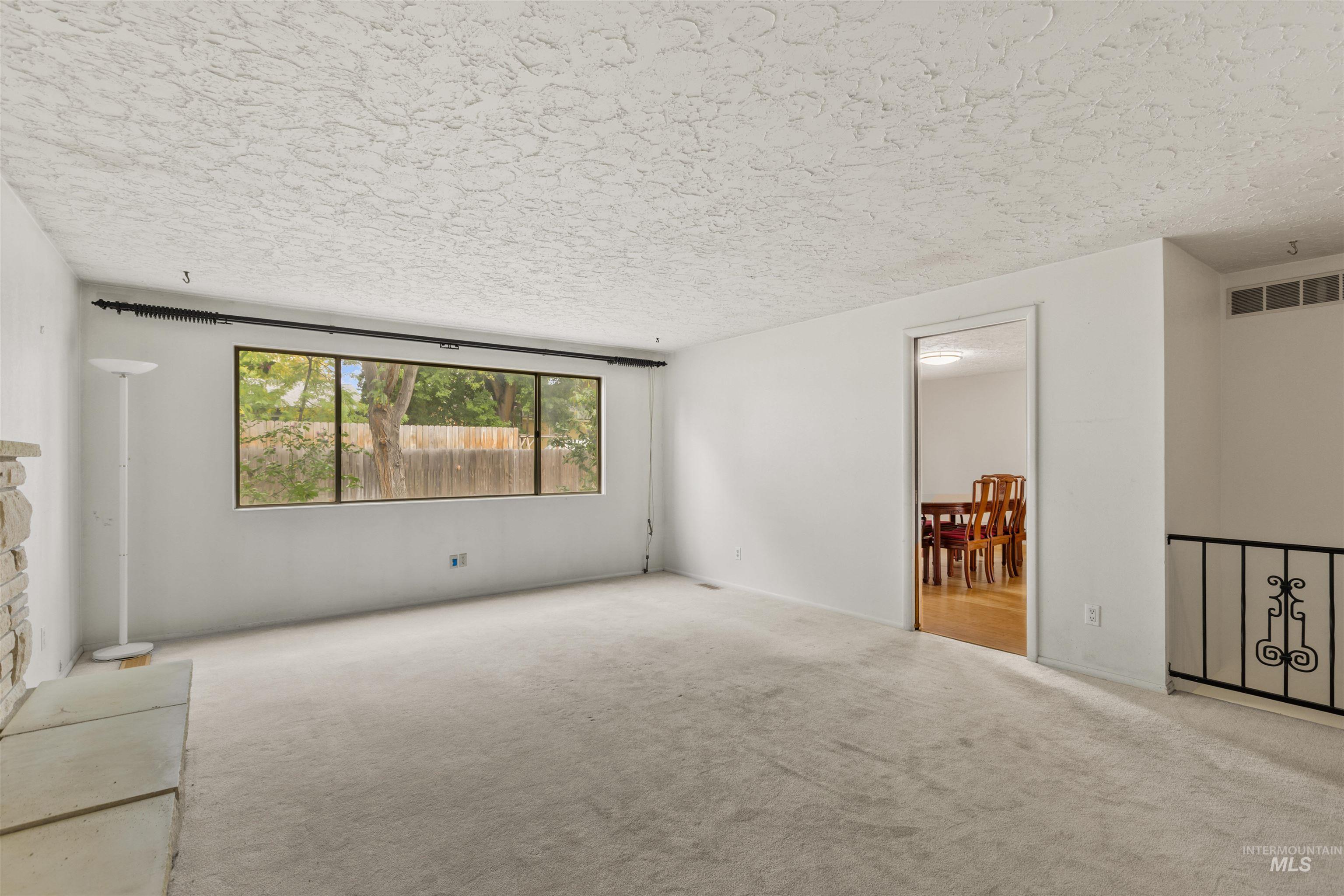 Unfurnished living room featuring carpet floors and a textured ceiling