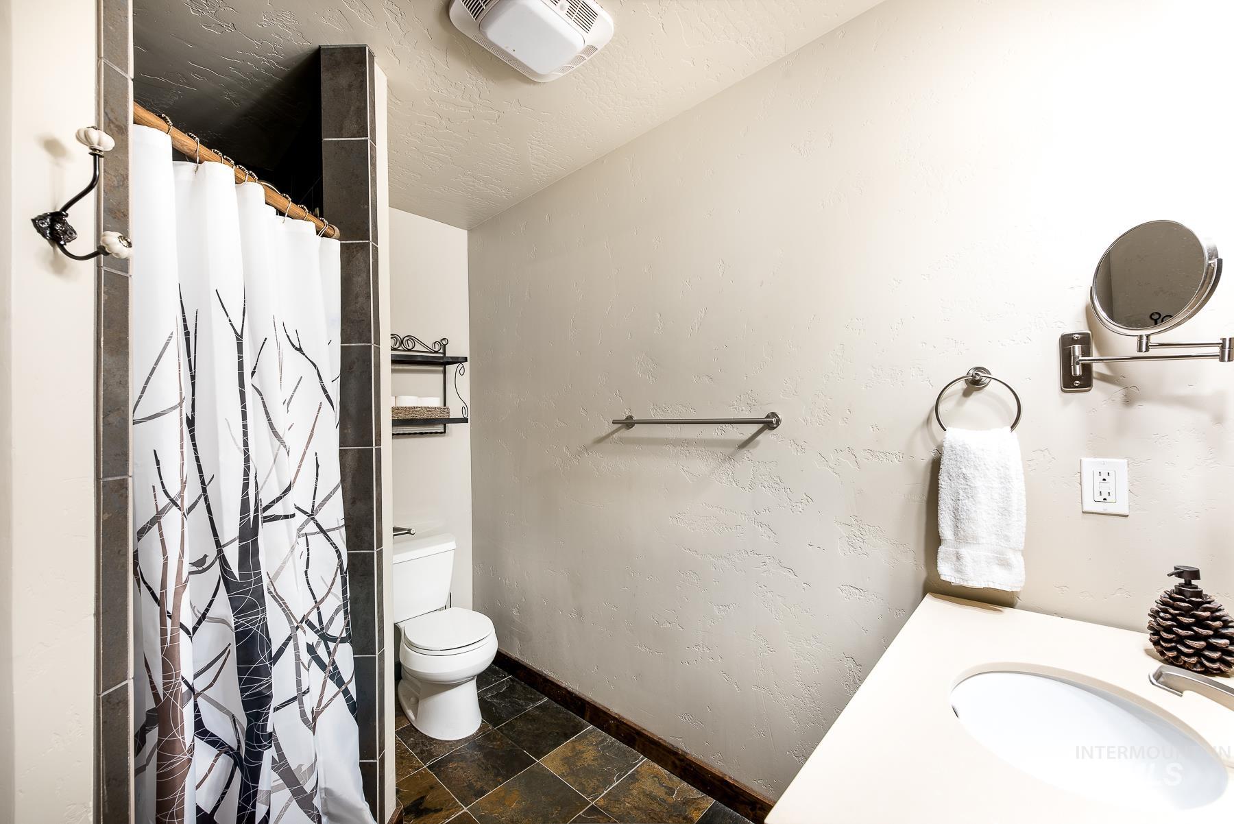 Full bath with a stall shower, dark stone finish flooring, a textured wall, vanity, and a textured ceiling