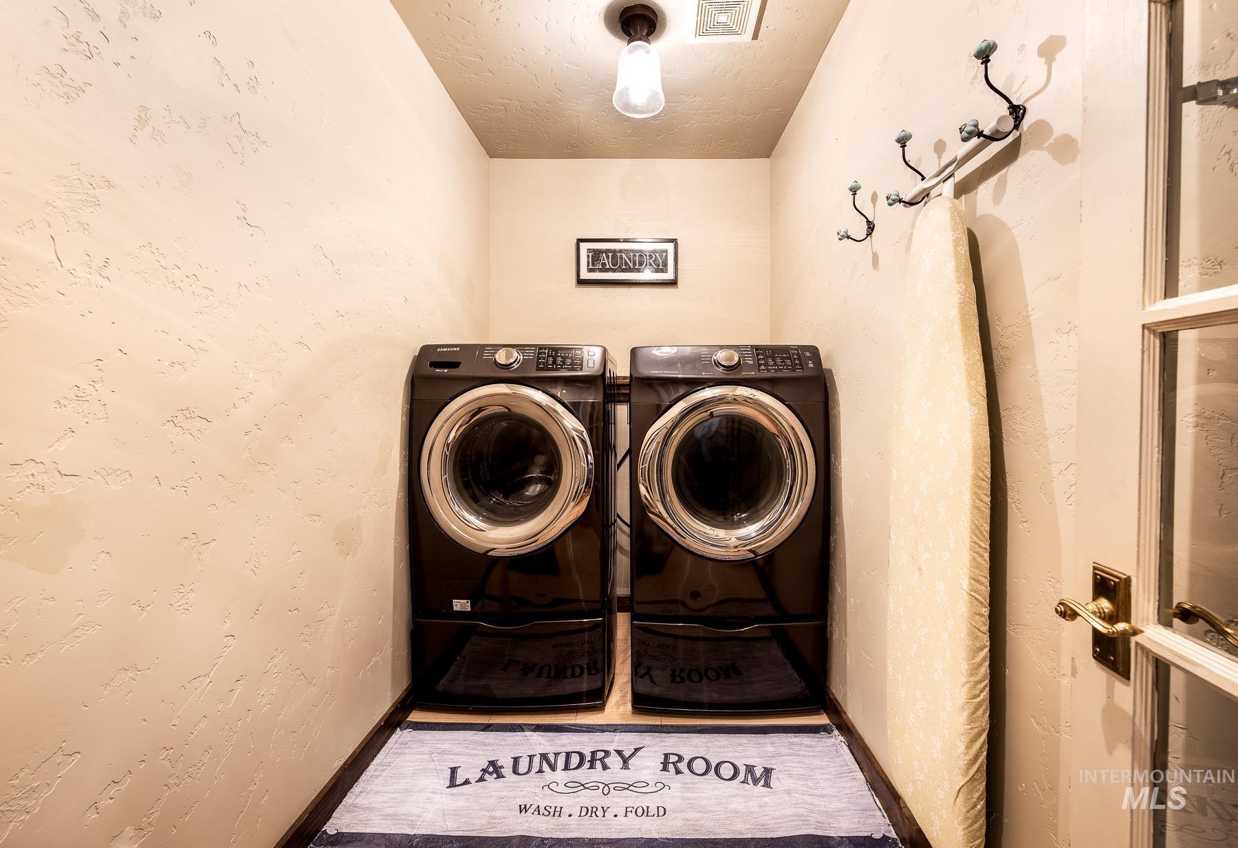 Laundry room featuring washing machine and dryer, a textured wall, and a textured ceiling