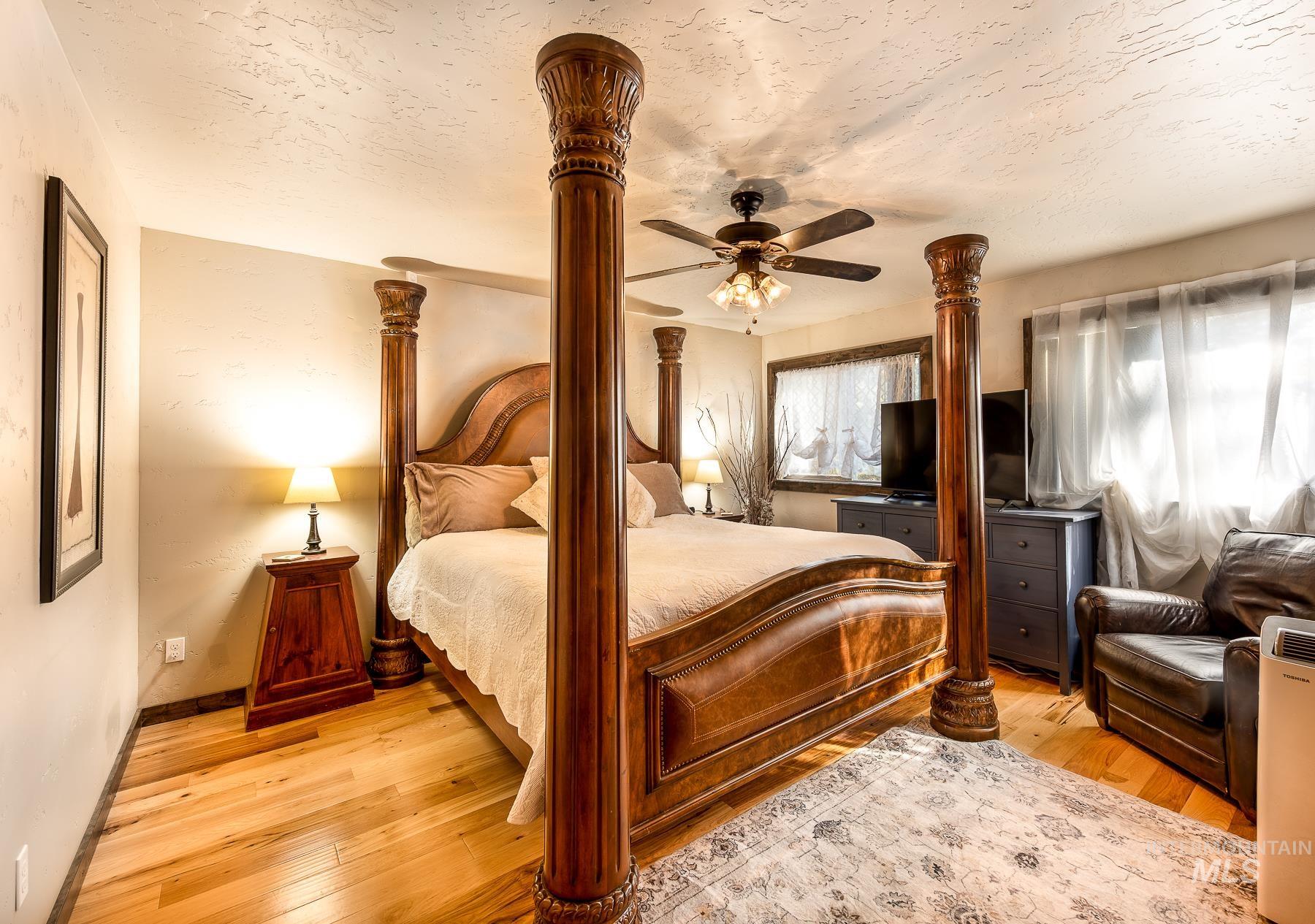 Bedroom with ceiling fan, light wood-type flooring, and a textured ceiling