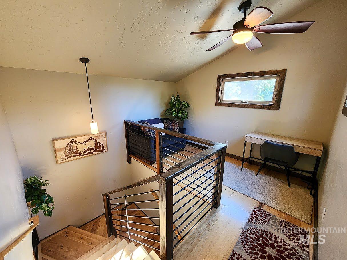 Stairway with wood-type flooring, a ceiling fan, and a textured ceiling