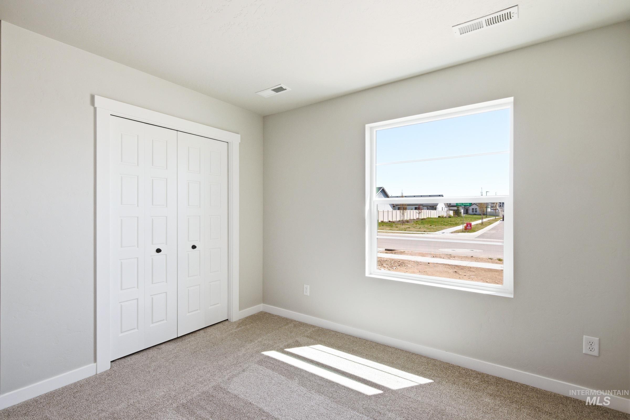 Interior room featuring light gray wall paint, white trim, and neutral carpet