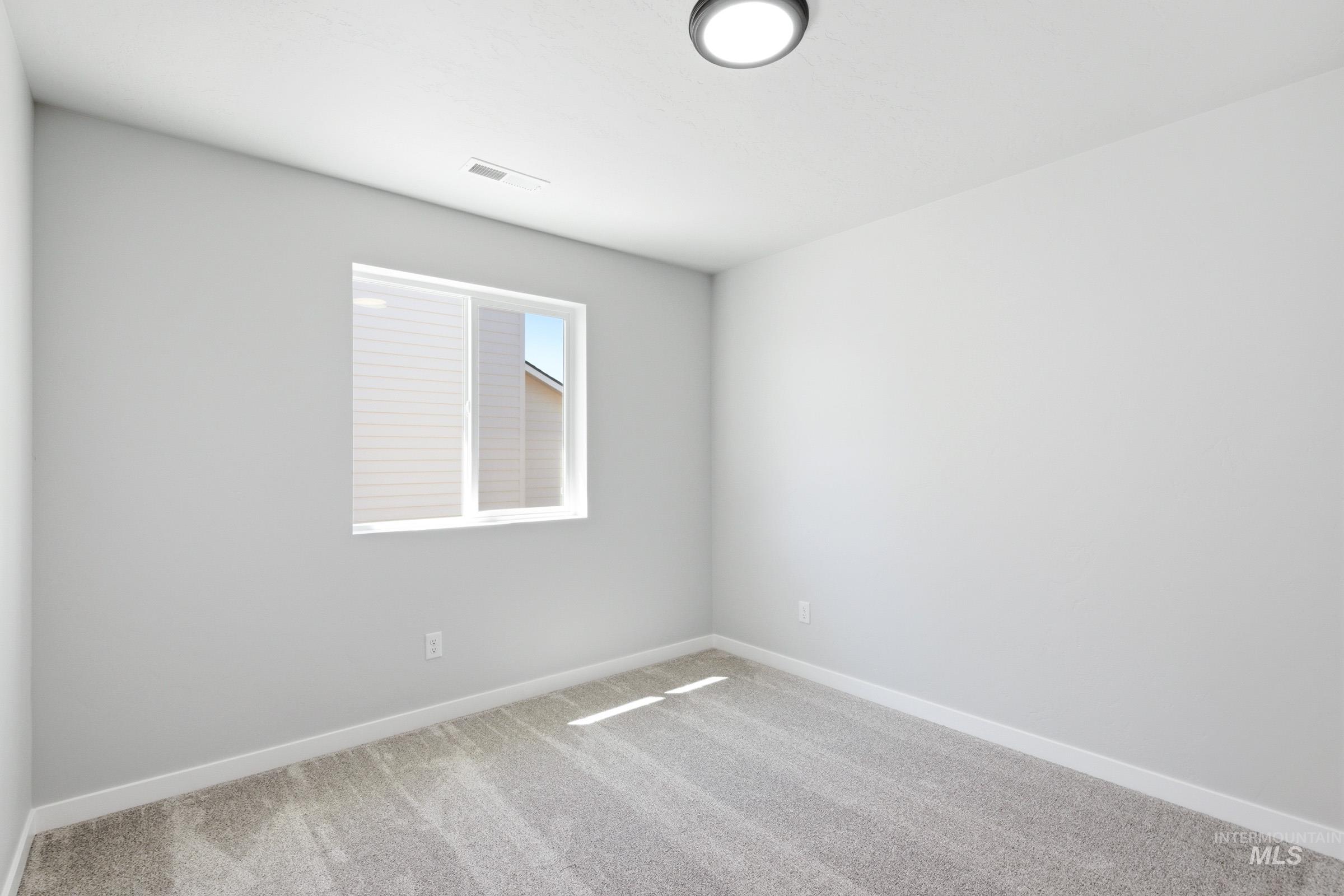 Neutral-toned room featuring a single window, light gray carpeting, and white baseboards