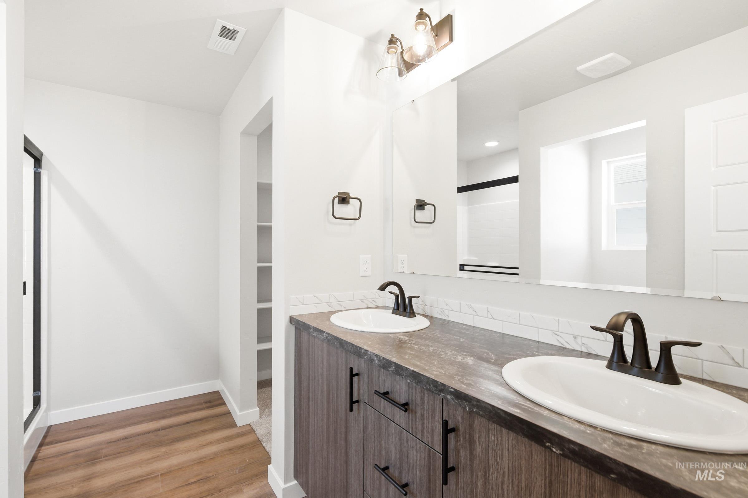 Dual vanity with dark wood-finish cabinetry, white oval sinks, and bronze-finish faucets