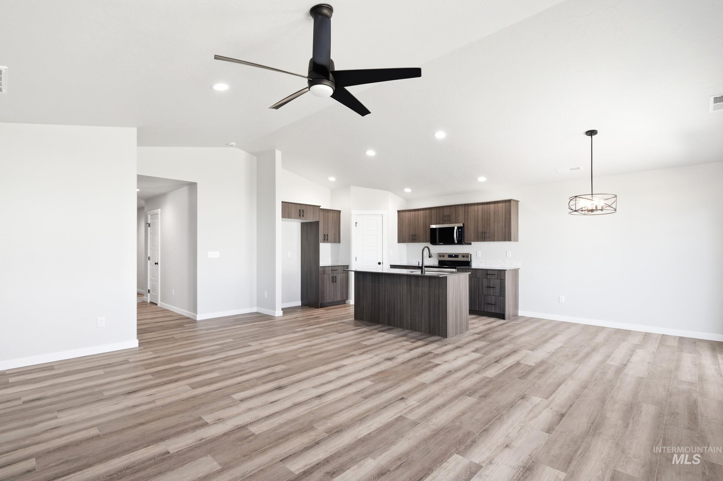 Open-concept living area featuring wood-finish flooring, vaulted ceilings, and recessed lighting