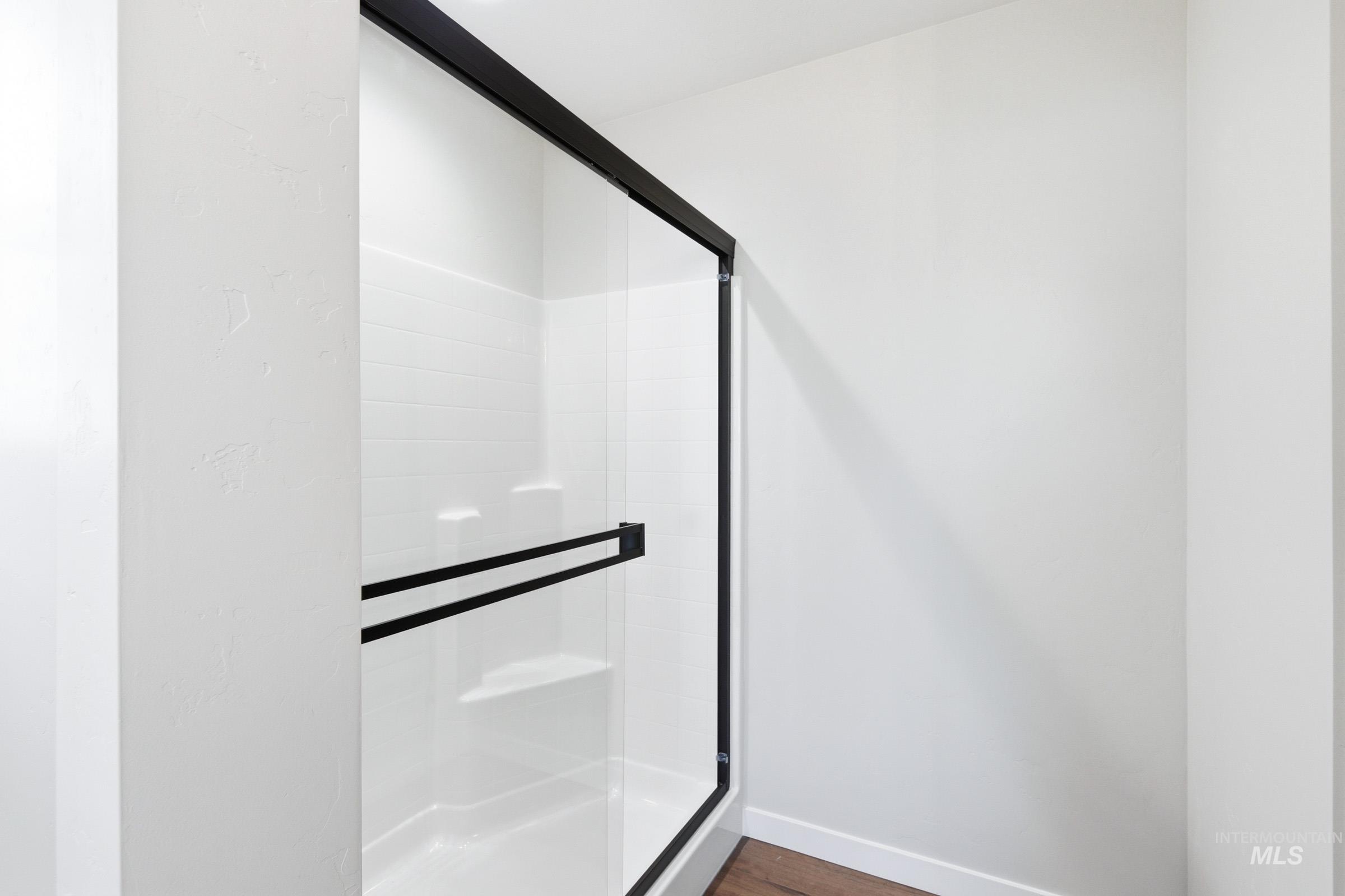 Modern shower enclosure featuring a clear glass door with matte black framing and hardware