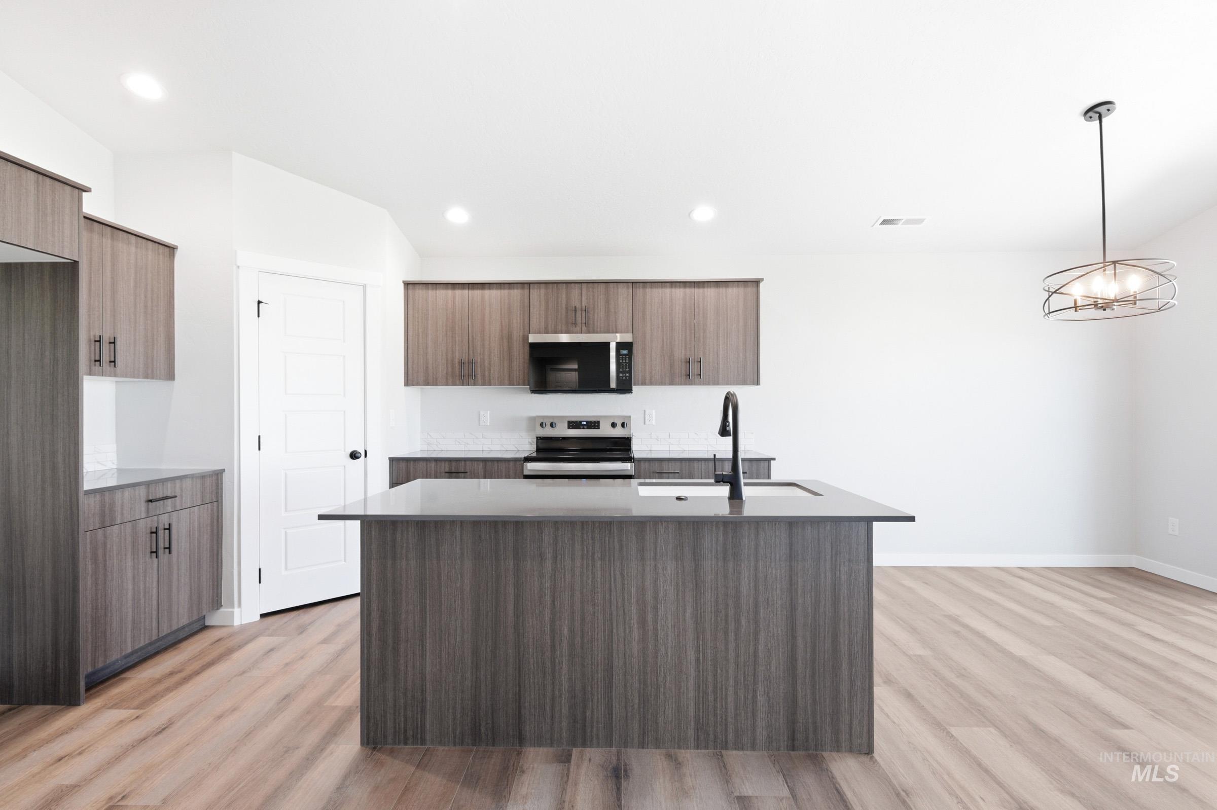 Kitchen featuring a central island with an undermount sink and a matte black faucet