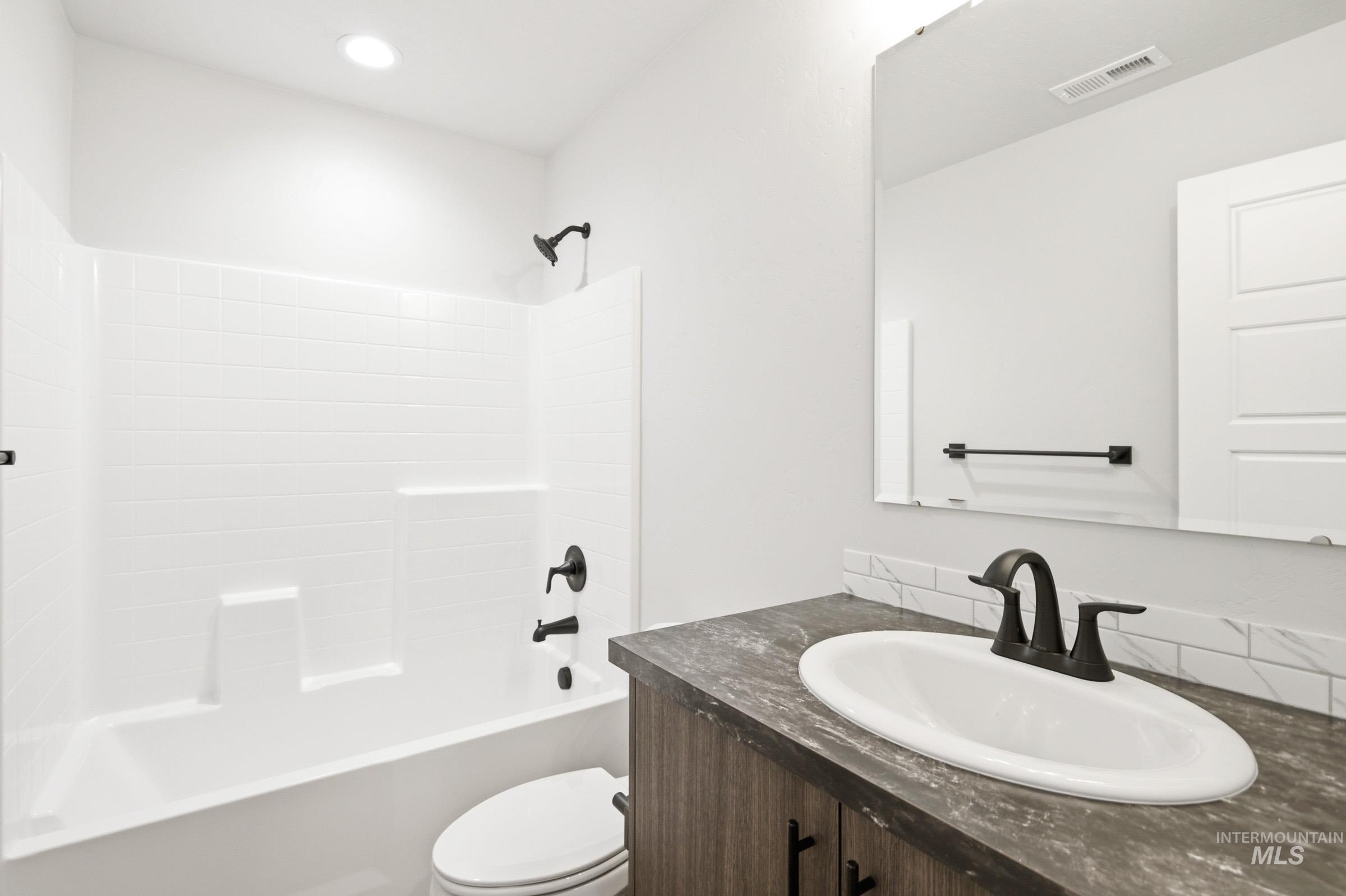 Bathroom featuring a modern vanity with an oval sink, dark countertop, and matte black faucet