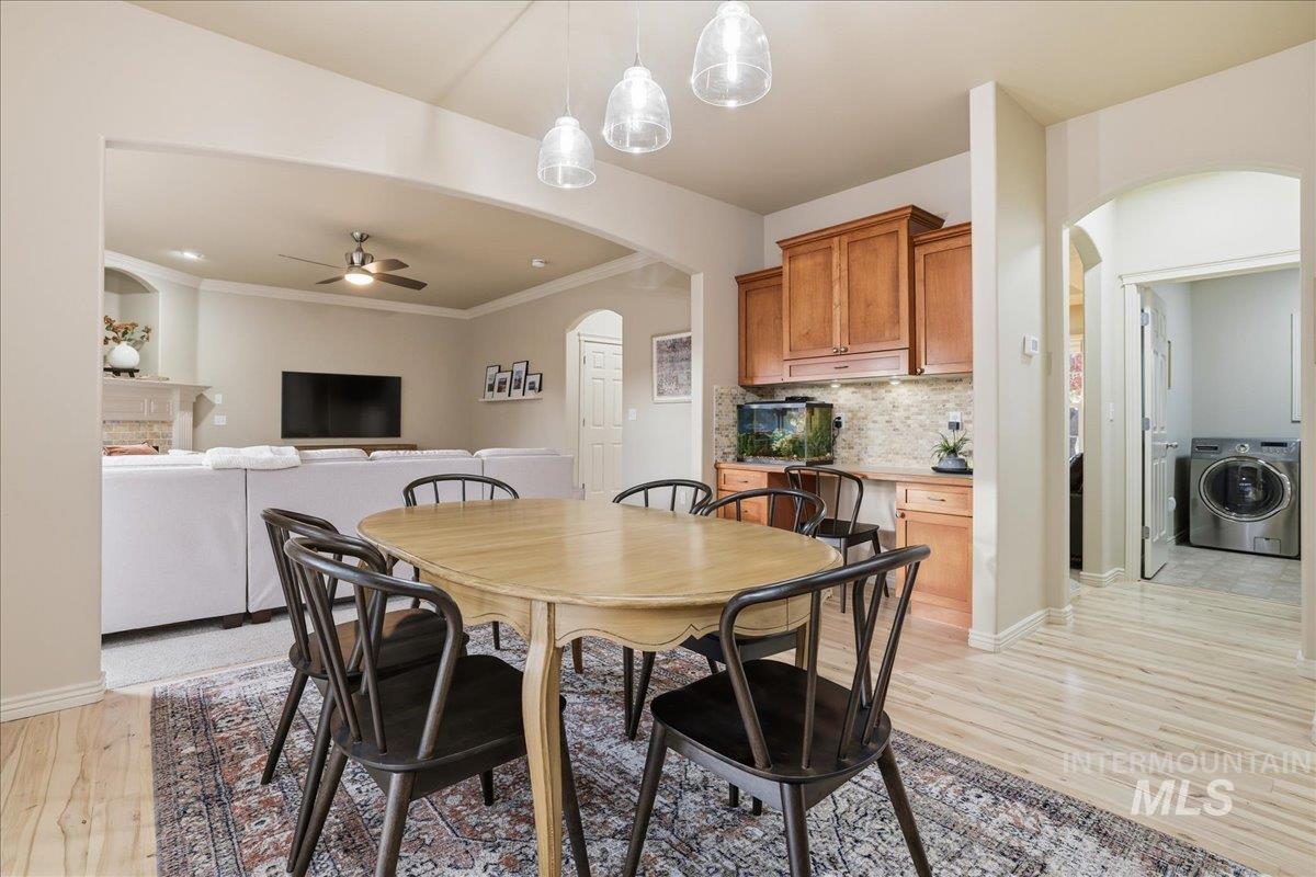 Dining space featuring arched walkways, washer / dryer, a ceiling fan, light wood-style floors, and a fireplace