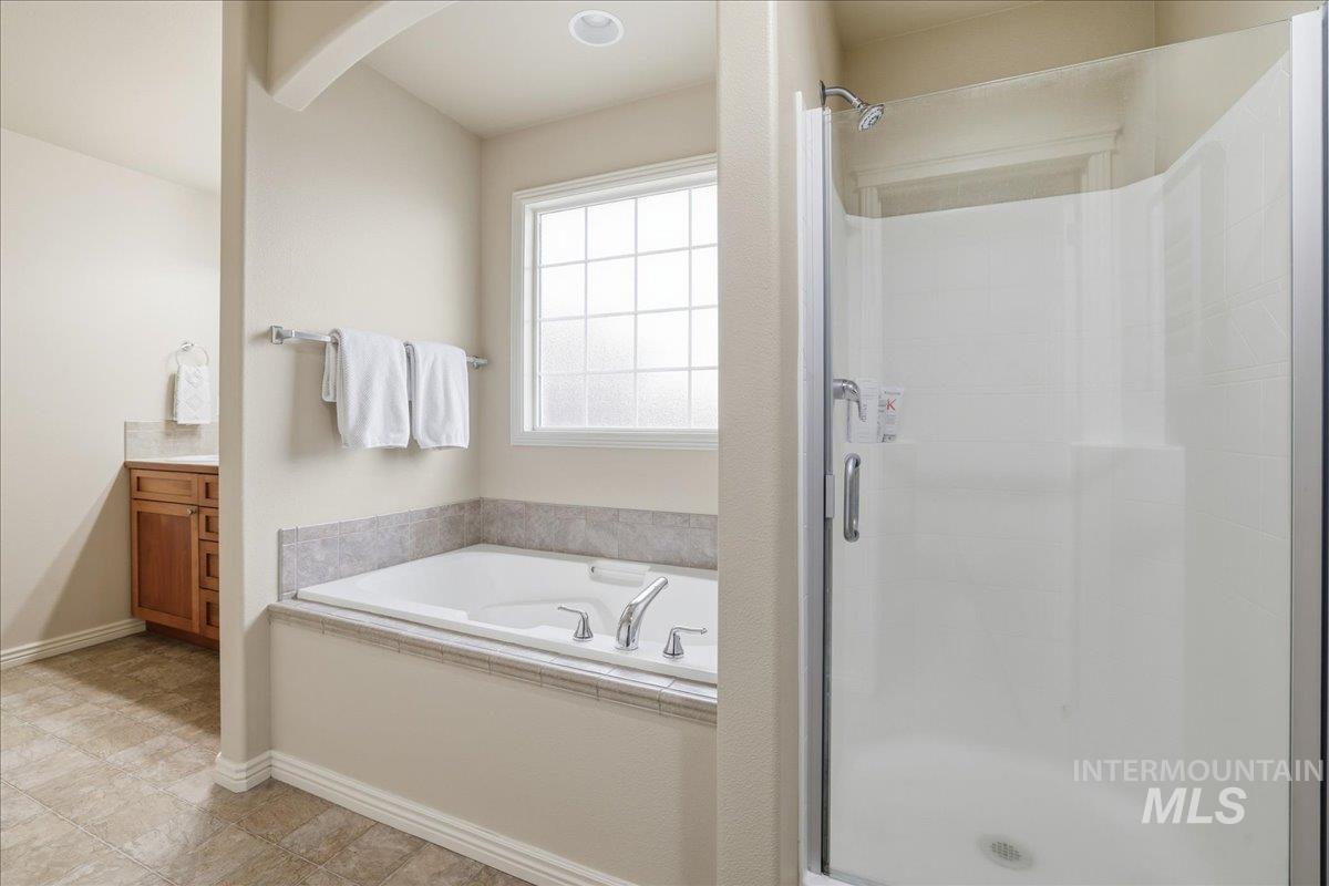Bathroom with a garden tub, a stall shower, and vanity