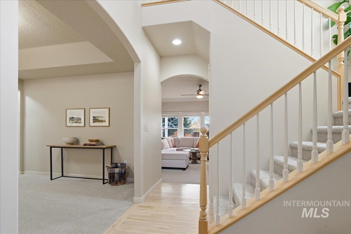 Foyer featuring stairs, light wood-style flooring, arched walkways, light colored carpet, and recessed lighting