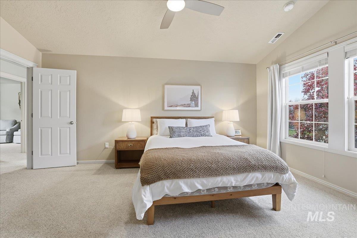 Bedroom with carpet floors, vaulted ceiling, a ceiling fan, and a textured ceiling