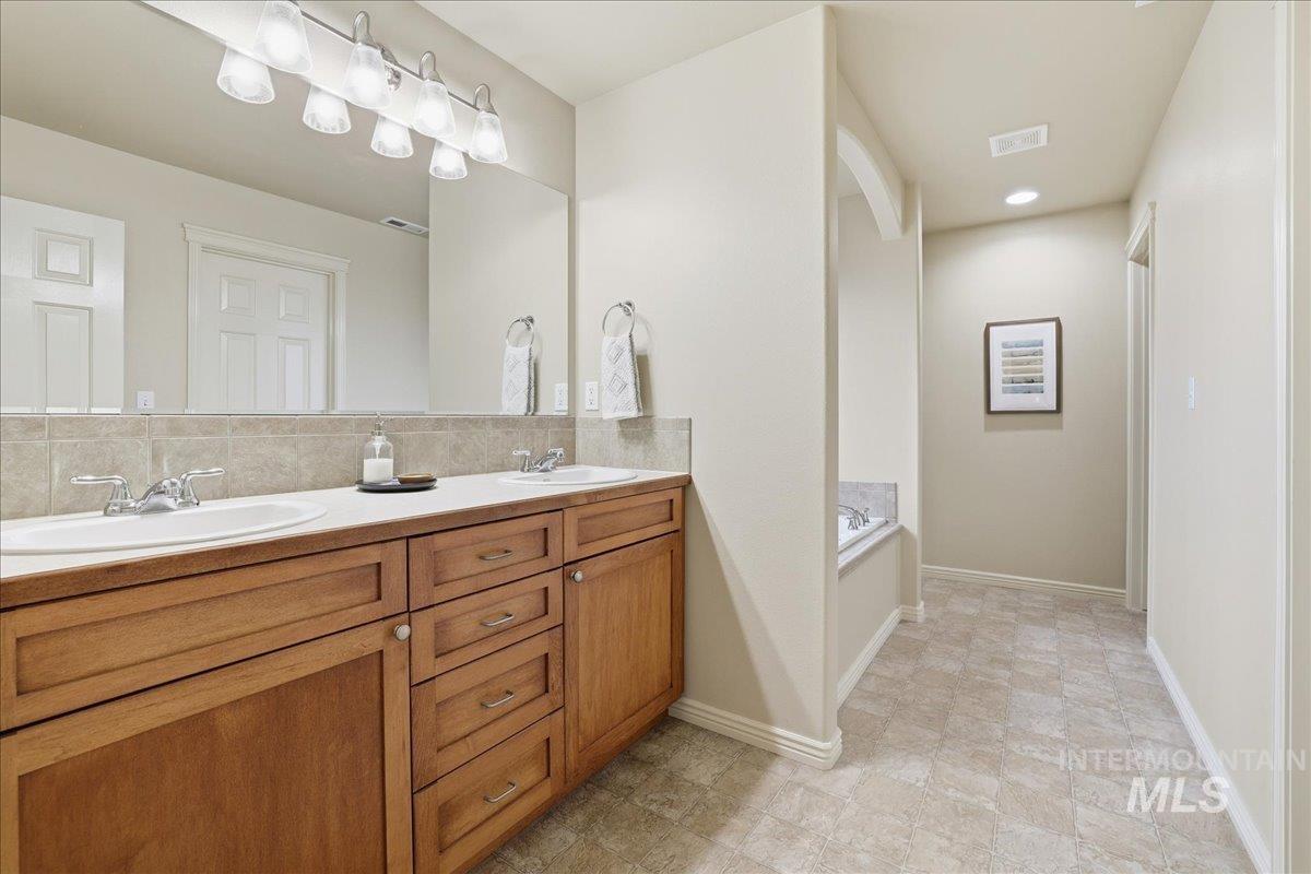 Bathroom with double vanity, a bath, and tasteful backsplash