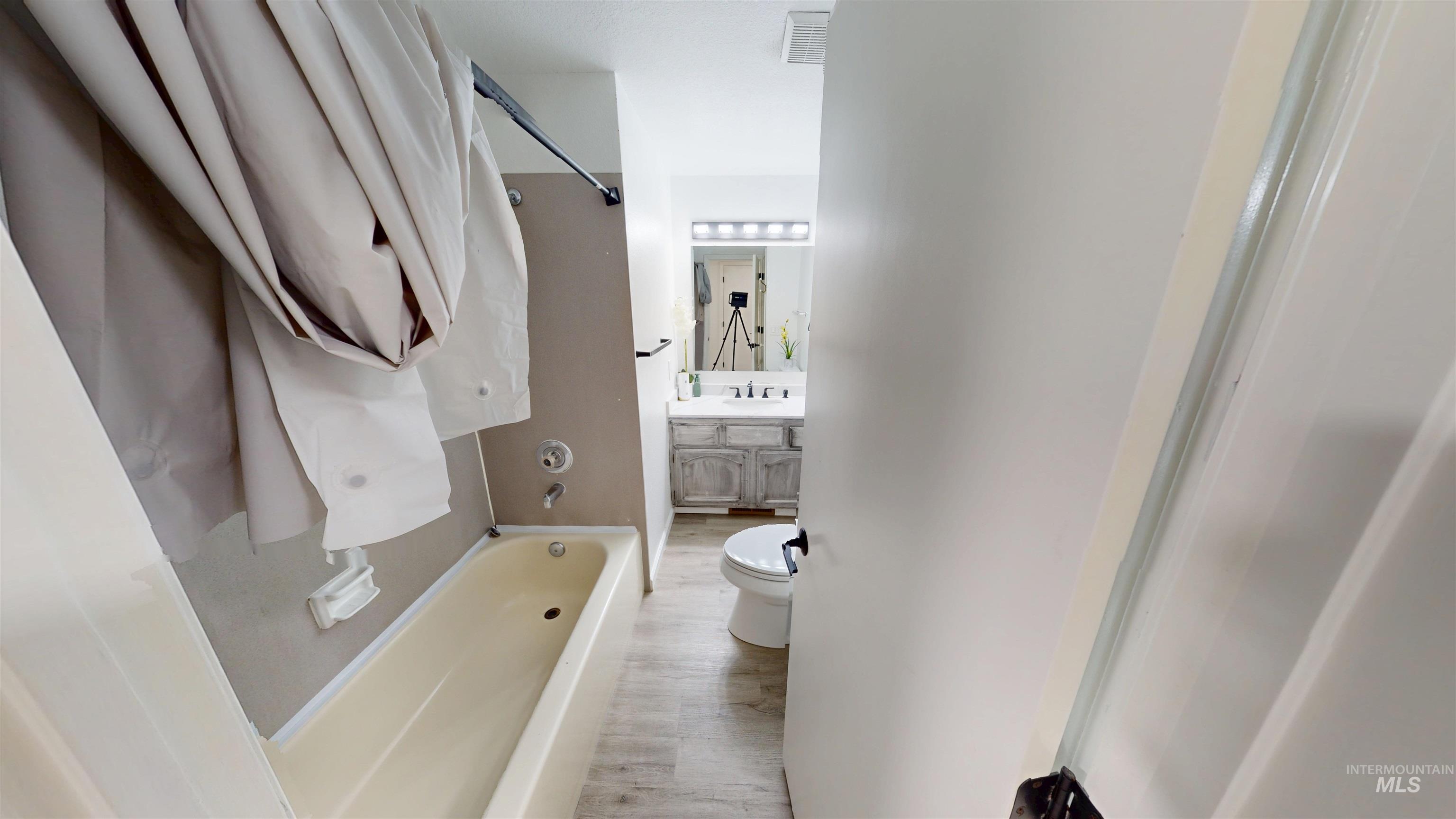 Full bathroom with vanity, light wood-type flooring, and  shower combination