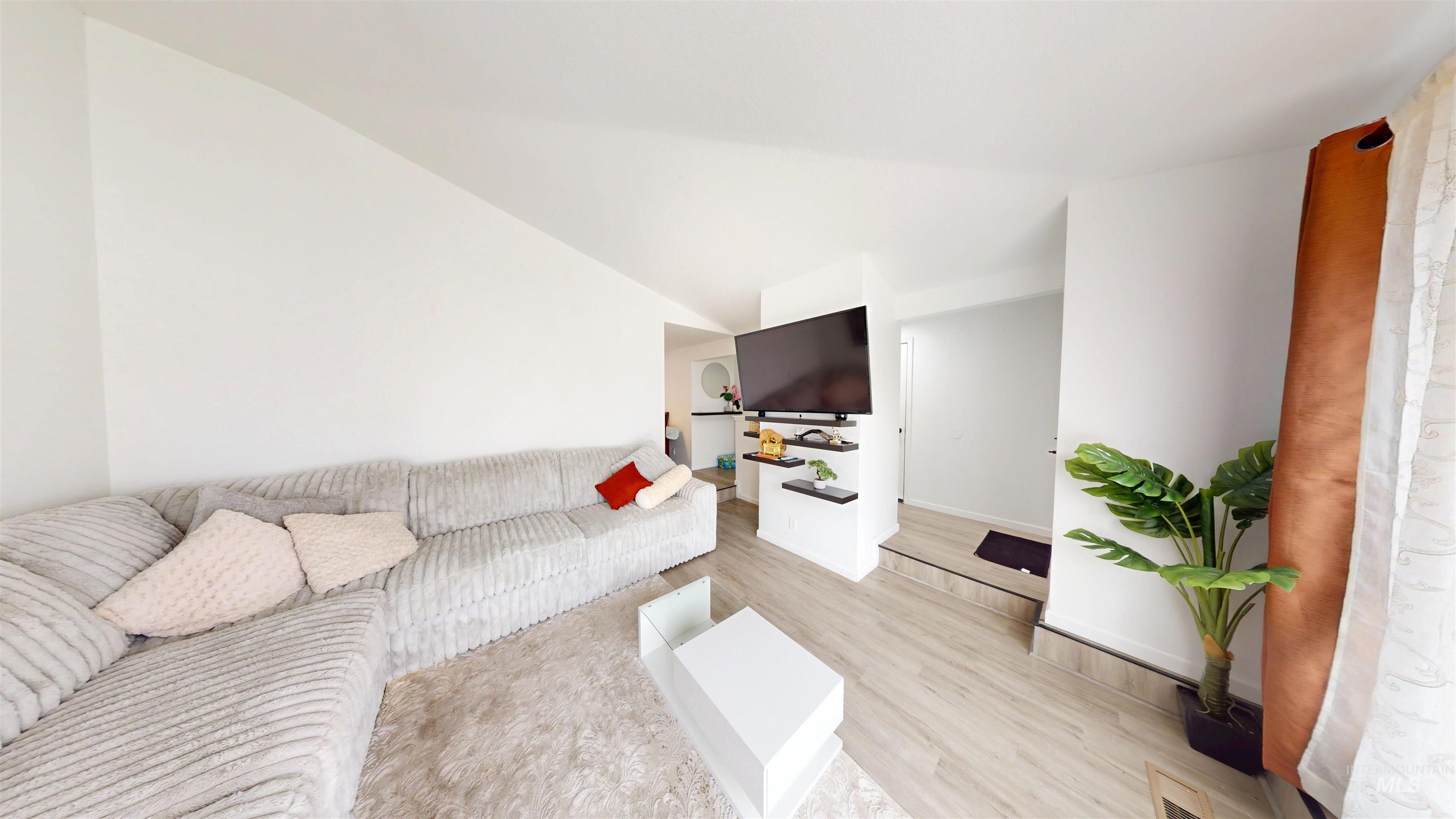 Living room with light wood-style flooring and vaulted ceiling