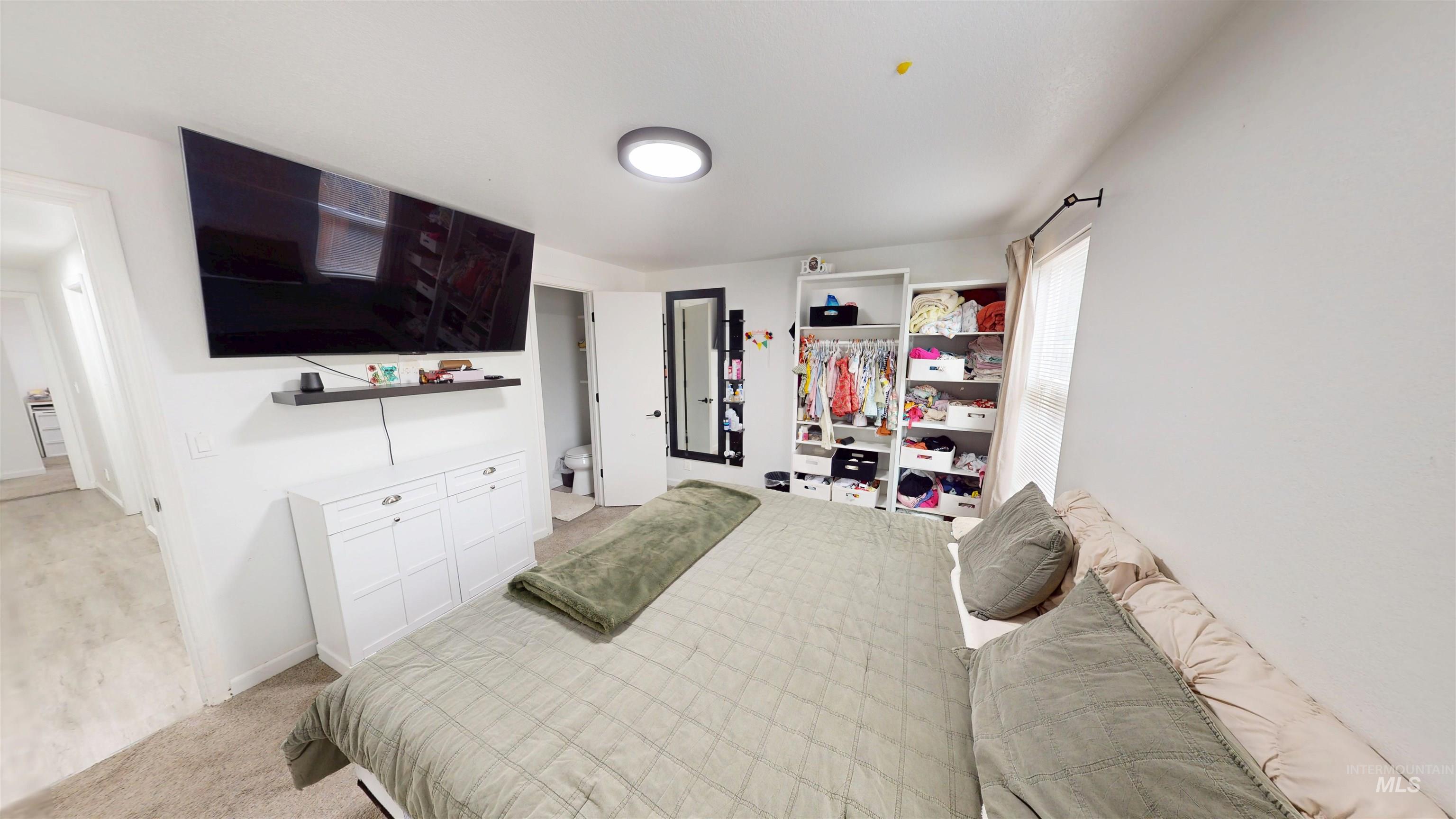 Bedroom with light colored carpet and a closet