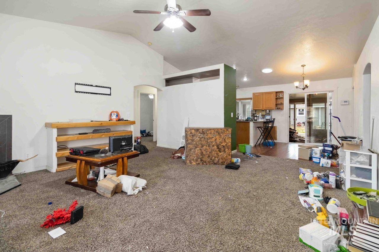 Living room featuring arched walkways, a ceiling fan, dark carpet, and lofted ceiling