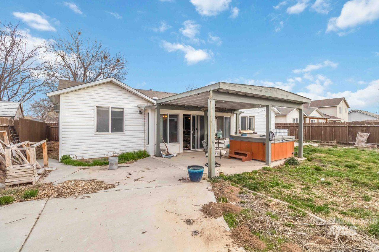 Back of house featuring a fenced backyard, a patio, and a hot tub