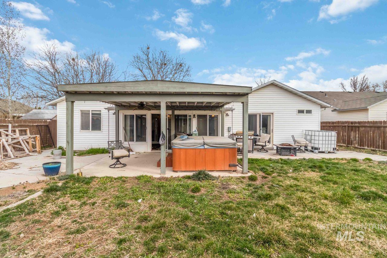 Rear view of property with a hot tub, a patio, a fenced backyard, ceiling fan, and a fire pit