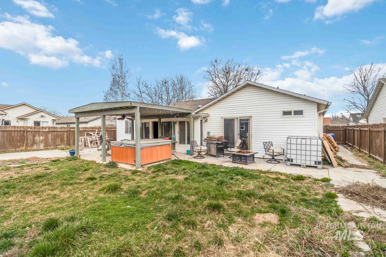 Rear view of property featuring a fire pit, a patio area, a hot tub, a fenced backyard, and ceiling fan