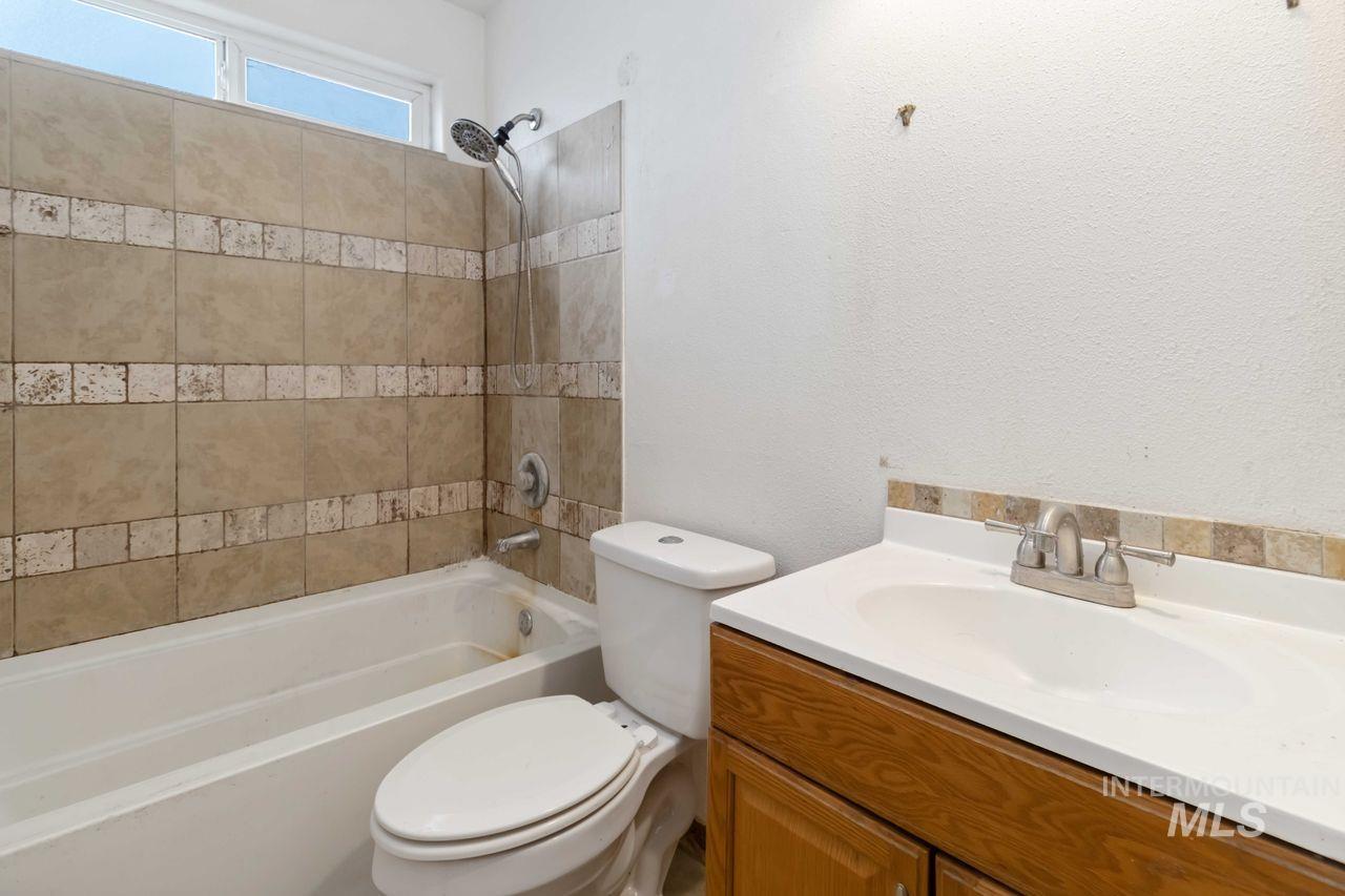 Bathroom featuring vanity,  shower combination, and a textured wall